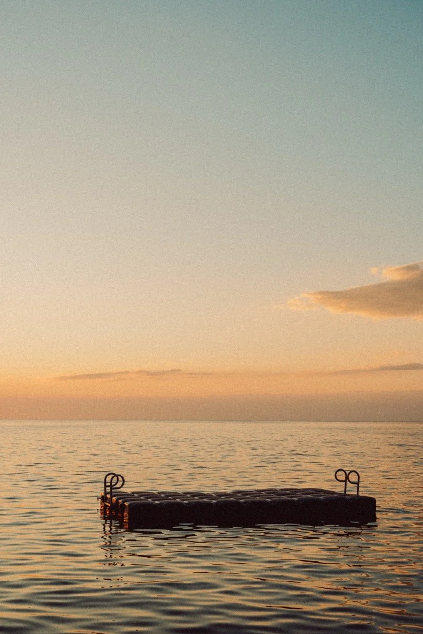 Floating dock on calm lake at sunset with a partly cloudy sky.