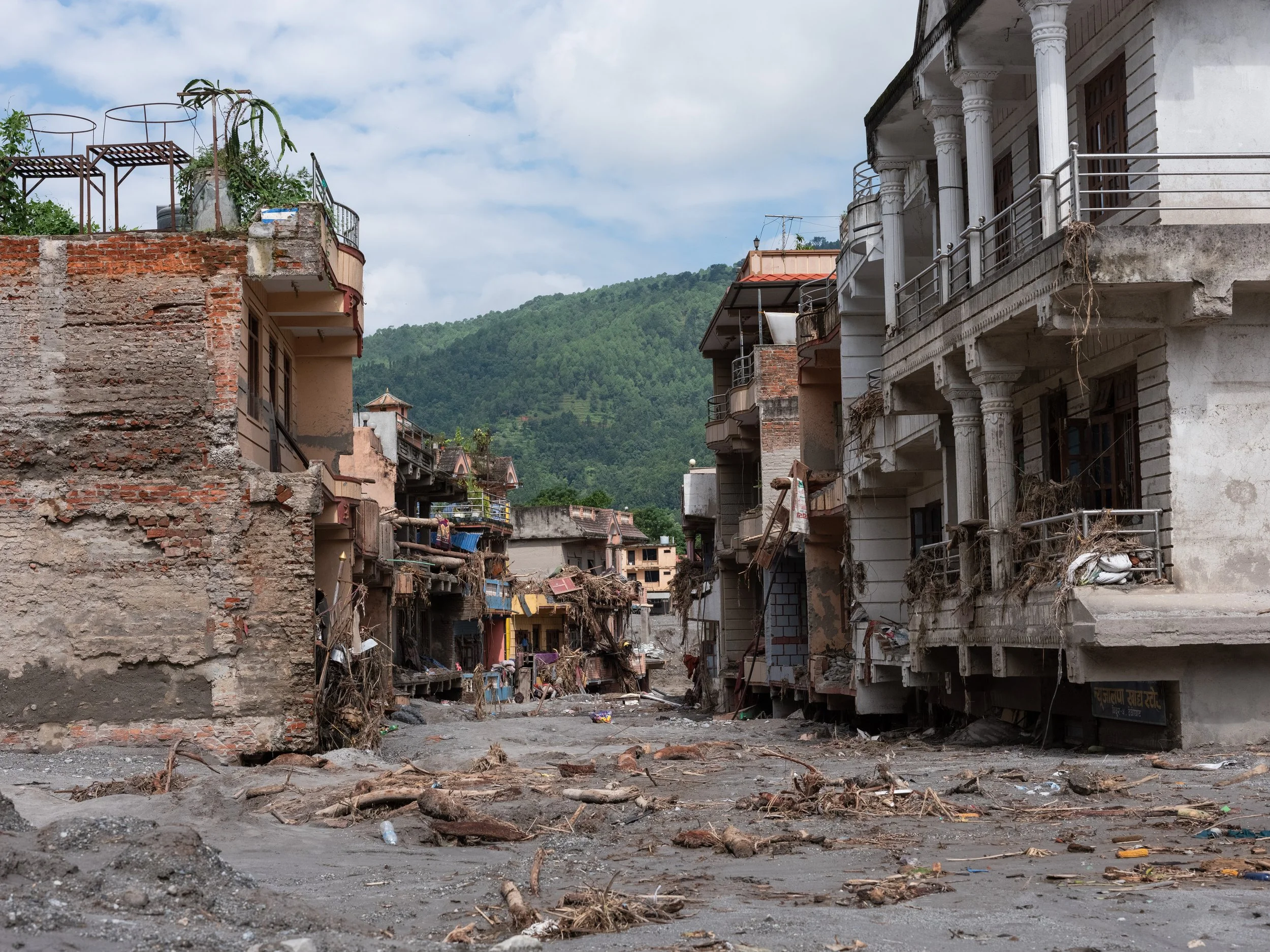 Flood damage and debris surrounding homes and buildings in a Nepal community following catastrophic flooding in August 2026.