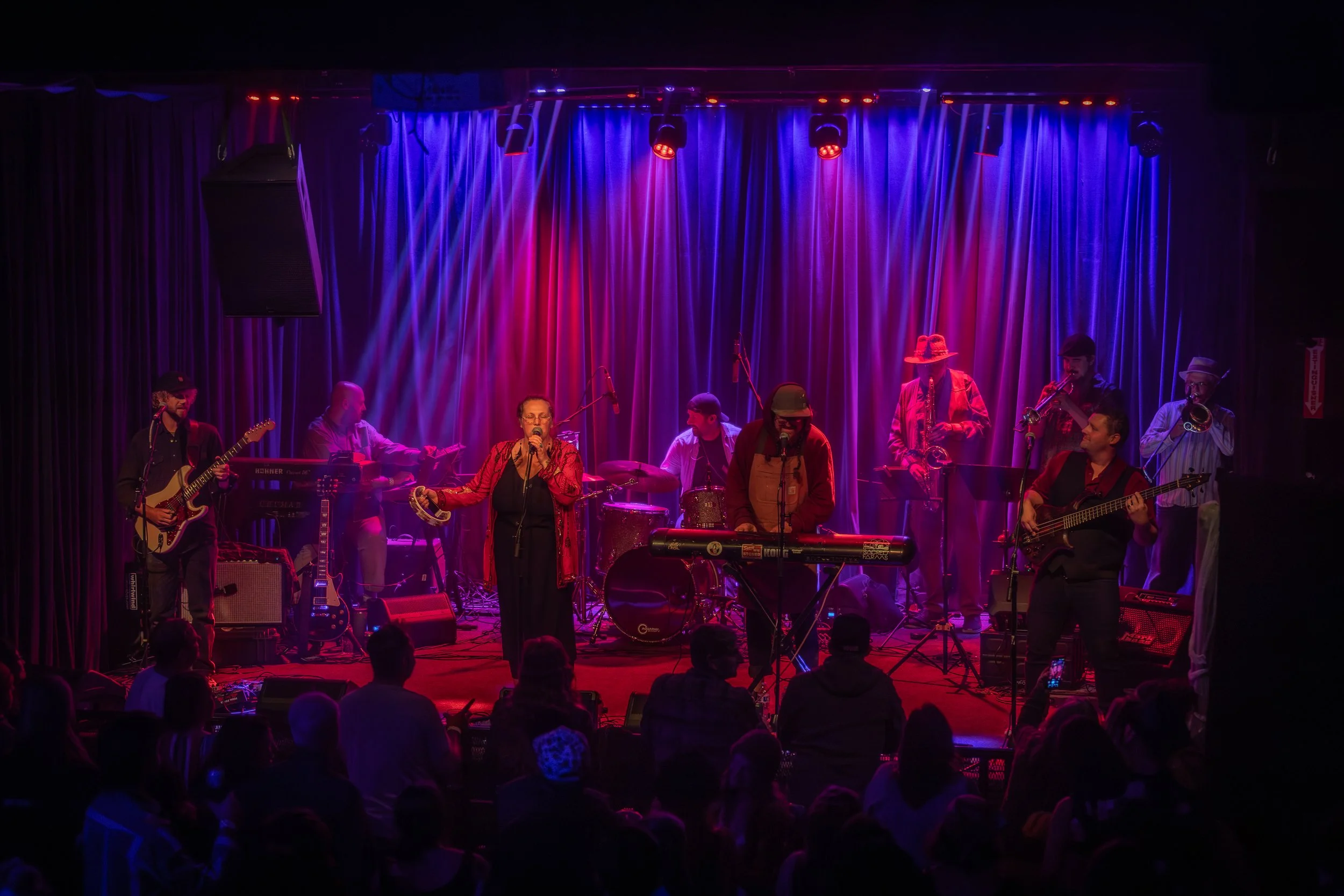 Meshem Jackson performing live on stage with his band at a music venue with colorful stage lighting.