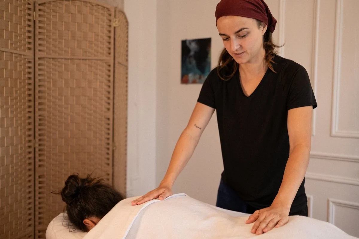 Holistic practitioner working on a client, room with woven divider, therapy session, relaxation, energy work.