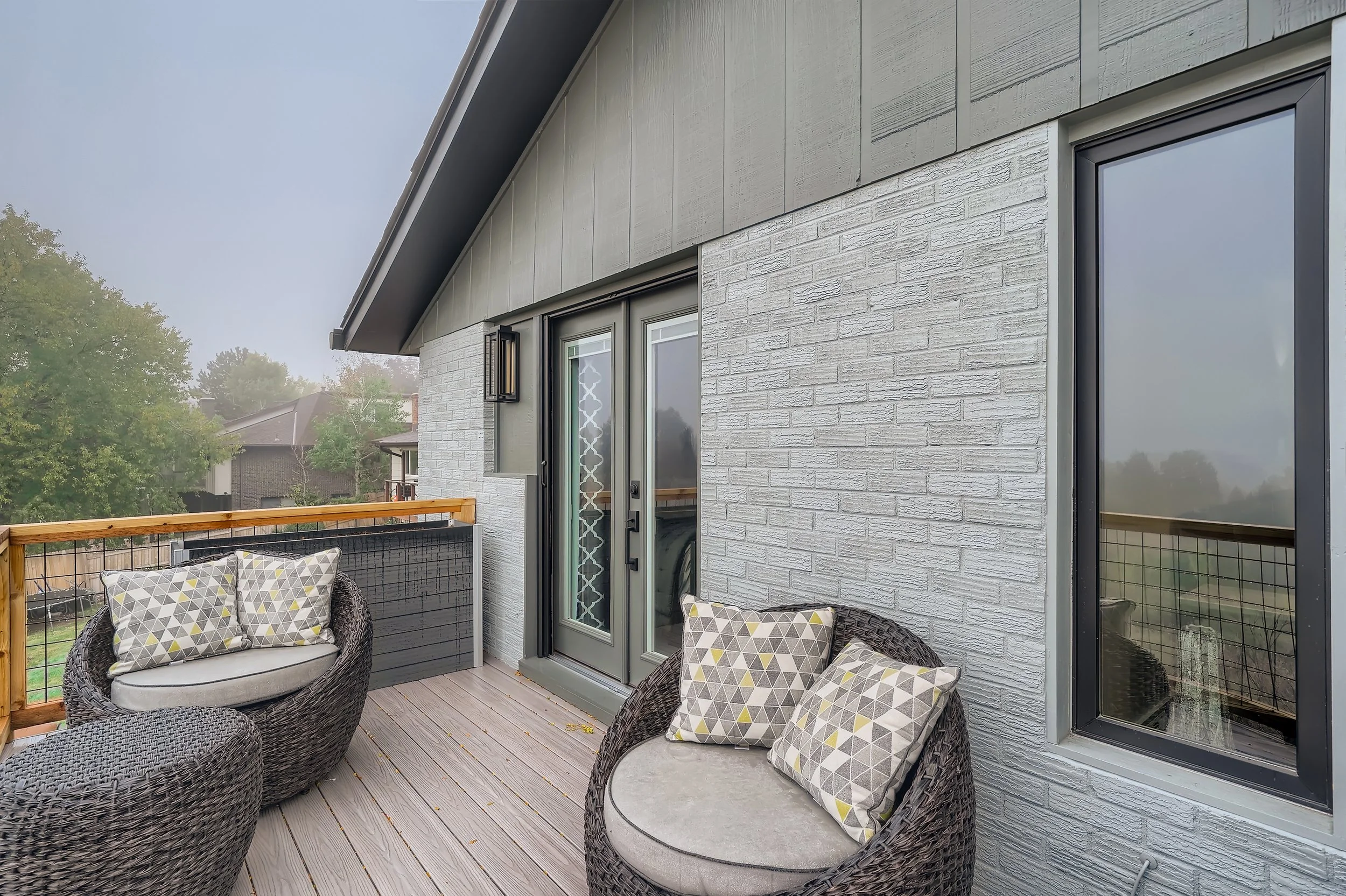 Composite deck balcony with wicker seating in Lakewood home remodel by Composite Deck Pros + SIG Construction.