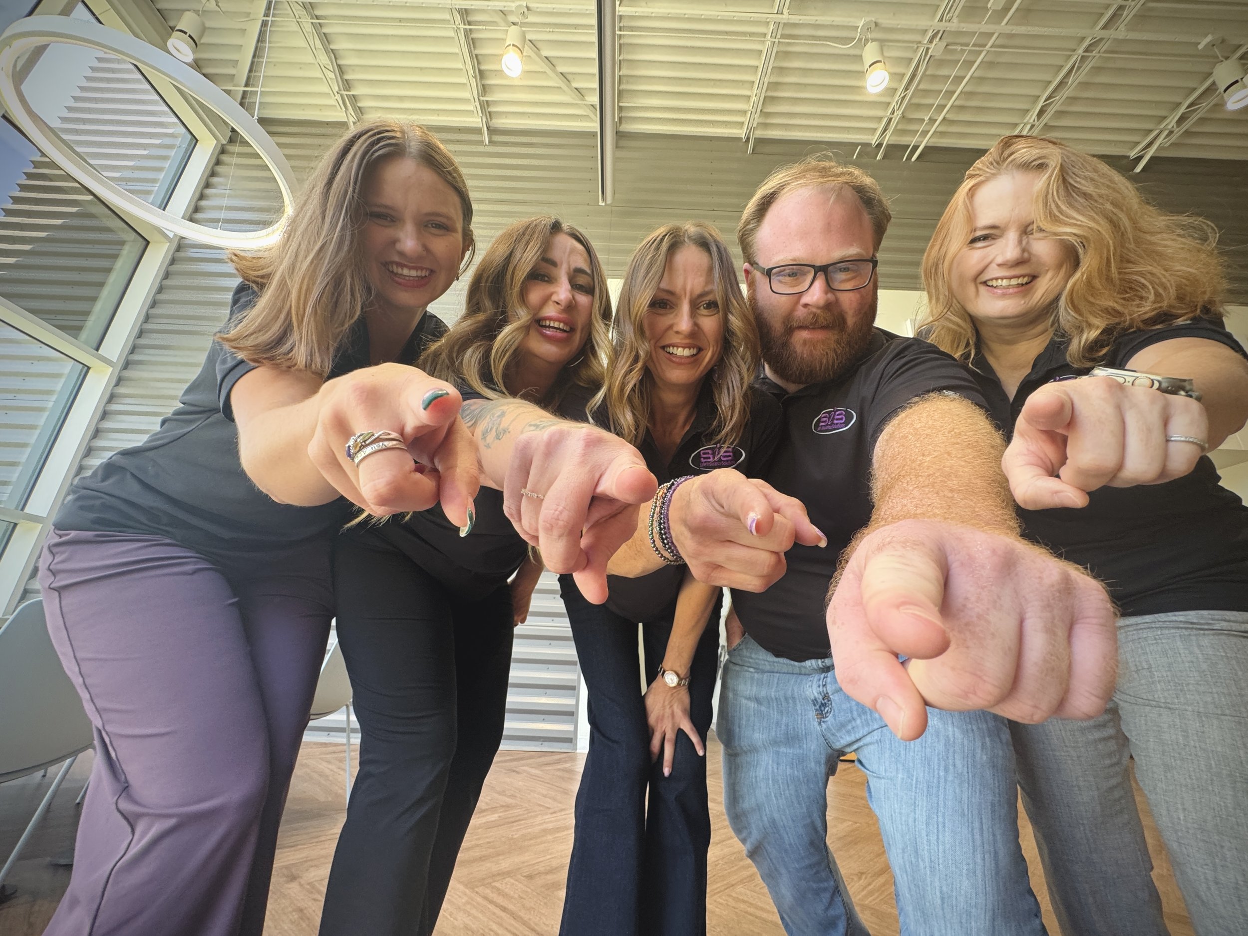 Safe Insurance Solutions team smiling and pointing toward the camera.