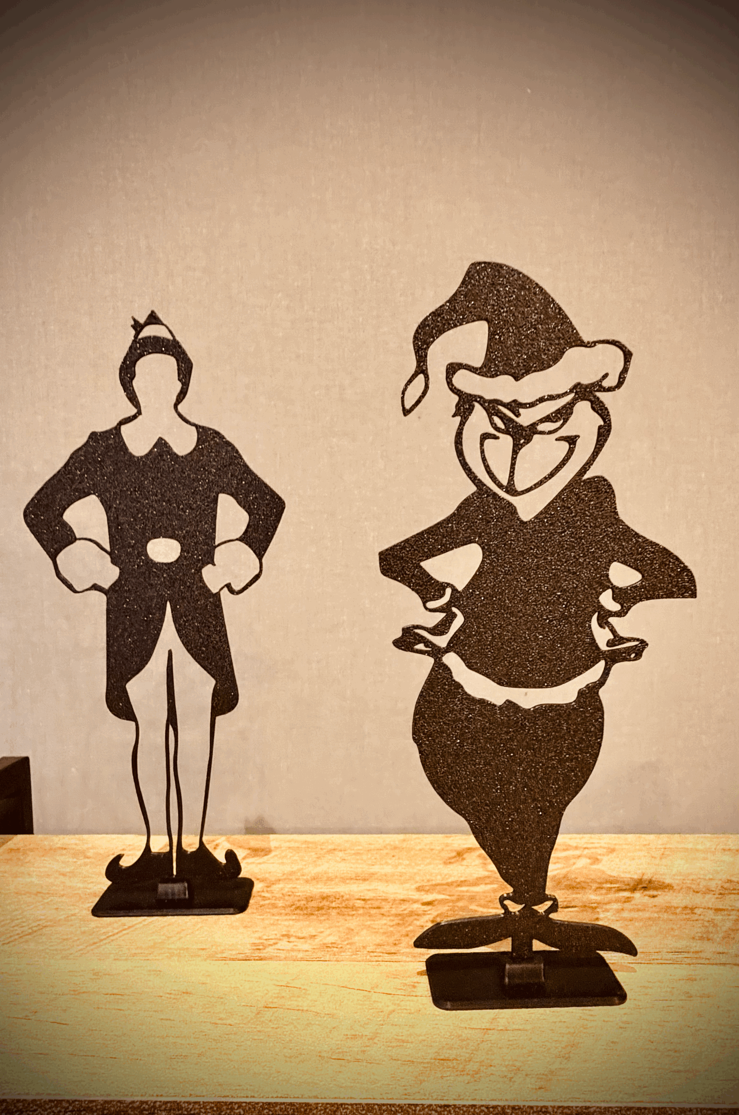 Two black metal standees of cartoon characters, one appears to be a woman in a dress with a bow in her hair, and the other a mischievous-looking man with glasses and a wide grin.