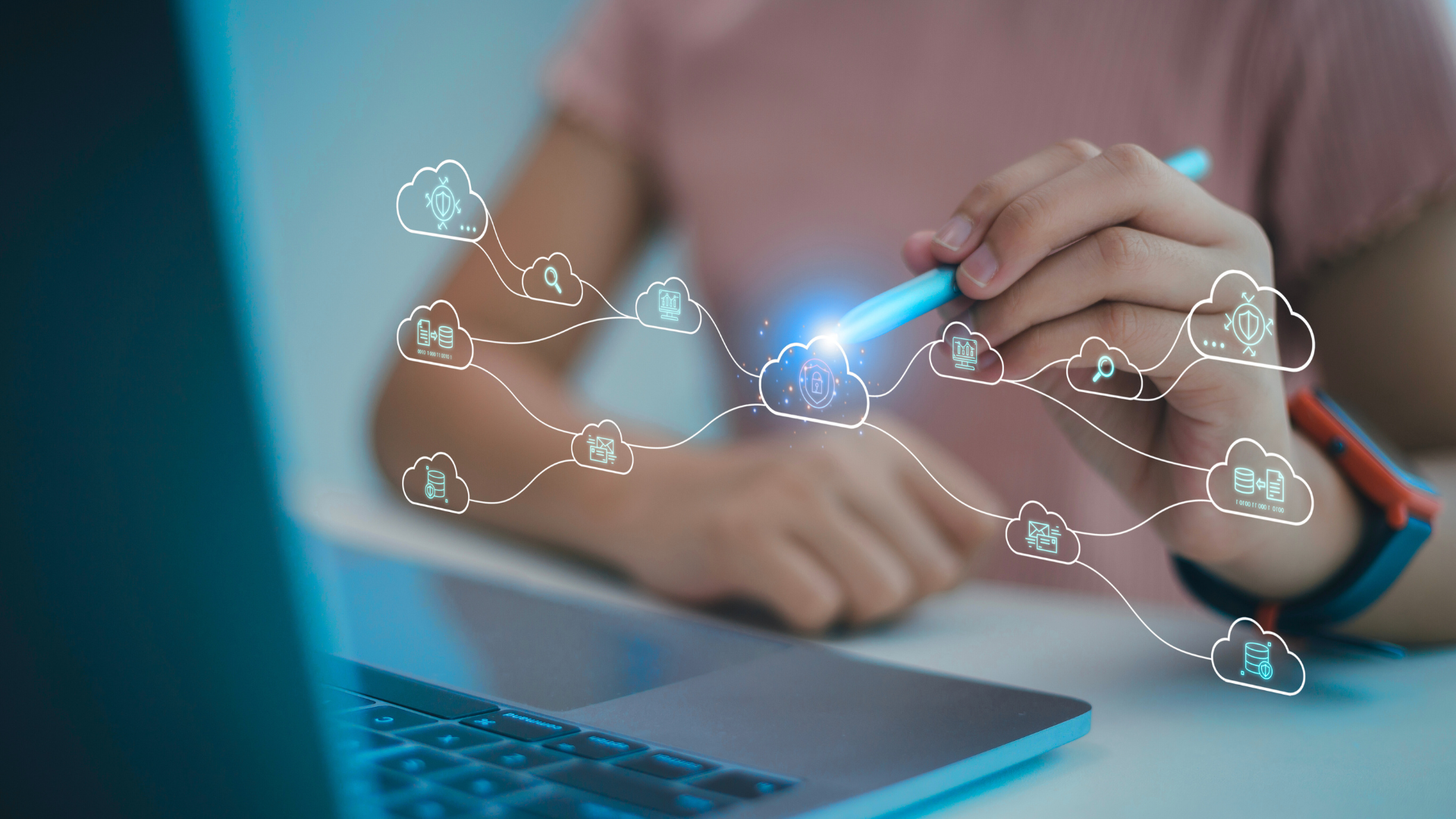 A person using a stylus on a laptop with digital cloud icons representing data security and cloud computing floating above the device.
