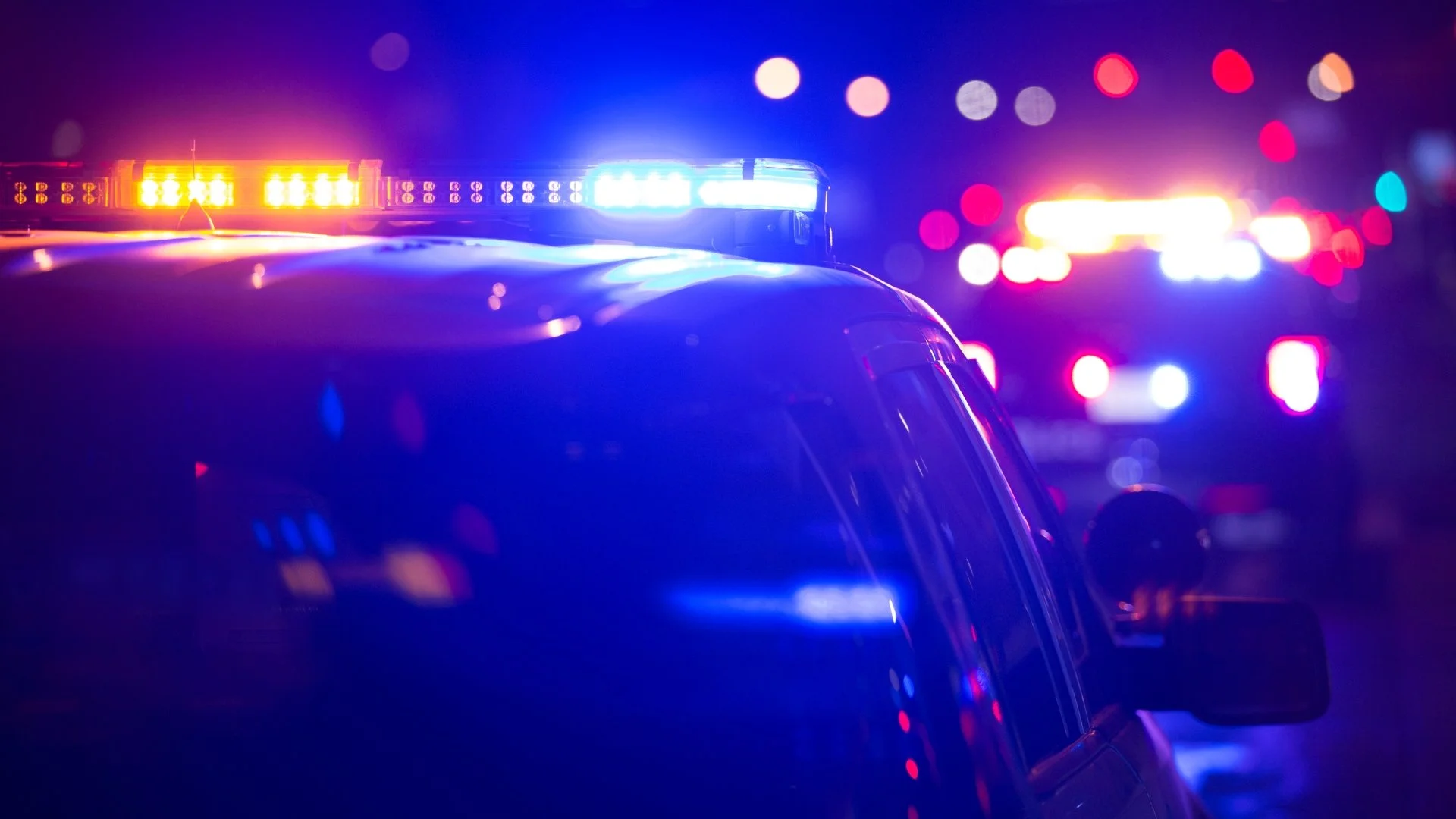 Police cars with flashing red and blue emergency lights at night.