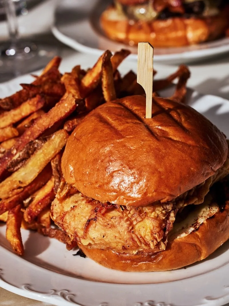 Not your average crispy chicken sandwhich: complex &amp; aromatic vadouvan fried chicken breast, sweet &amp; hot turmeric pickles, dill cr&egrave;me fra&icirc;che, &amp; pommes frites. Cozy, classic, and the perfect Tavern plate to sink your teeth in
