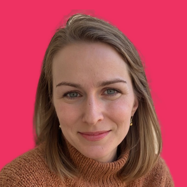 Woman smiling with curly hair against a pink background.