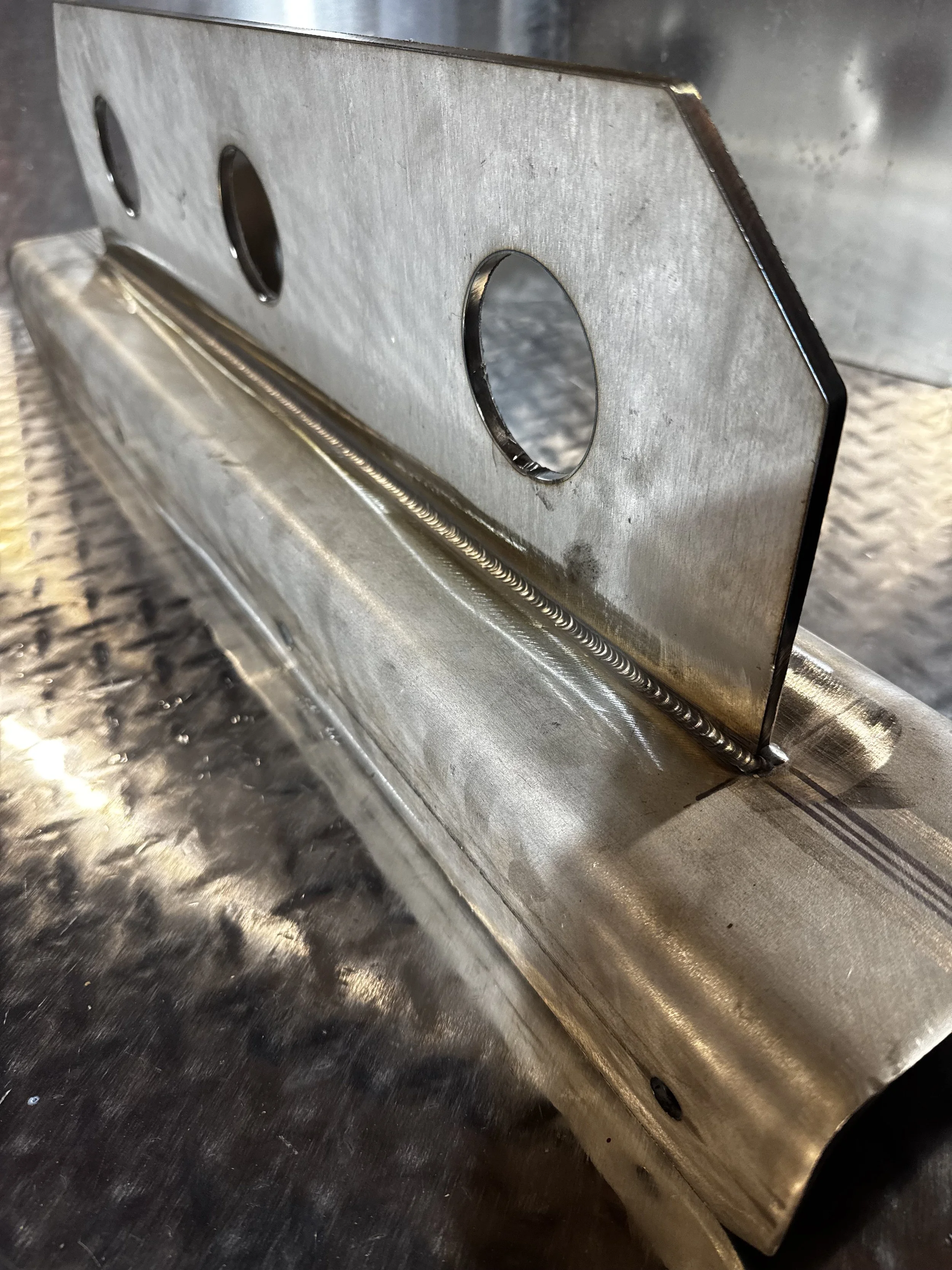 Close-up of a metal bracket with circular holes attached to a metal surface.