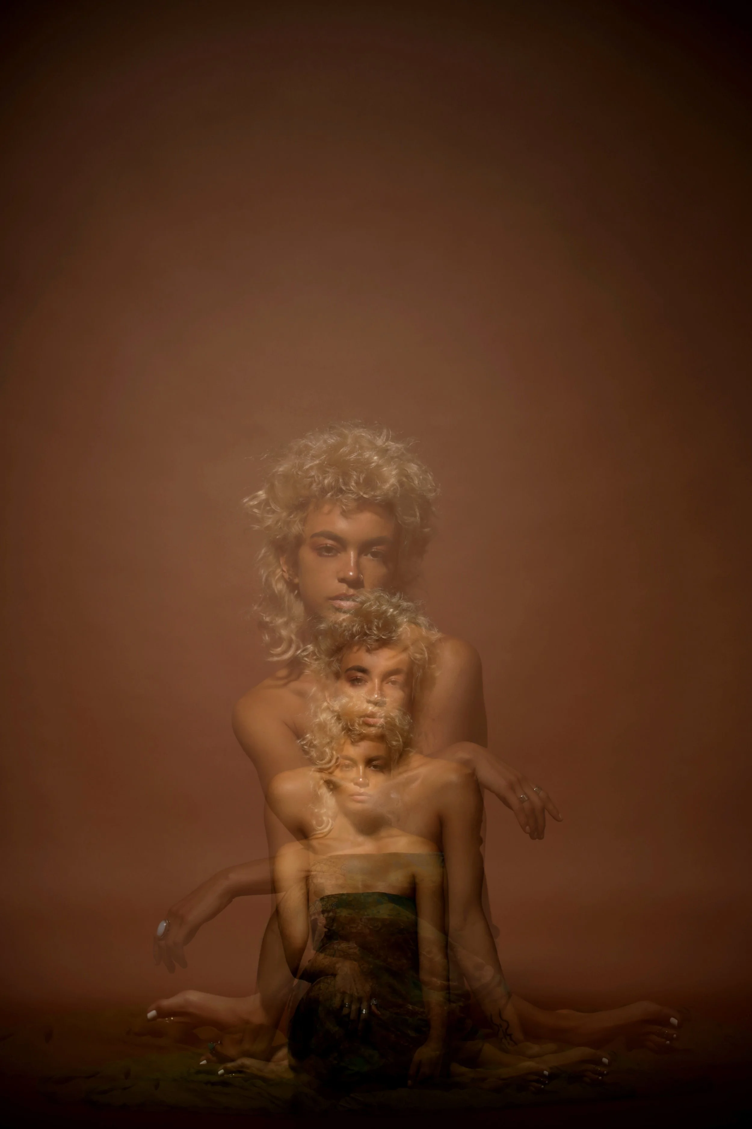 A layered, artistic photo collage of a woman with curly blonde hair, displaying multiple transparent overlapping images of herself in different poses against a brown gradient background.