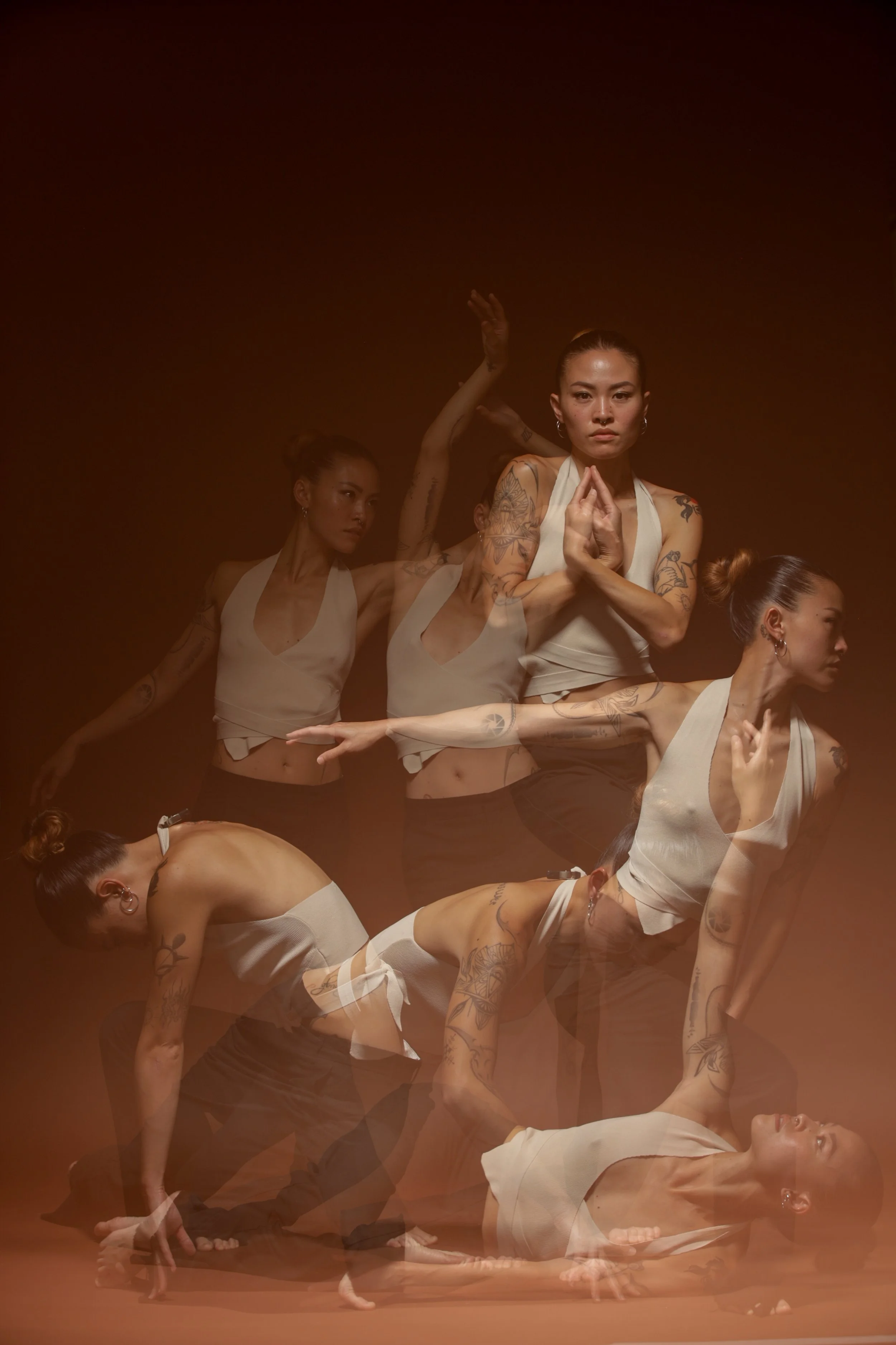 Multiple women with tattoos practicing yoga or meditation in a layered, artistic photo with warm lighting.