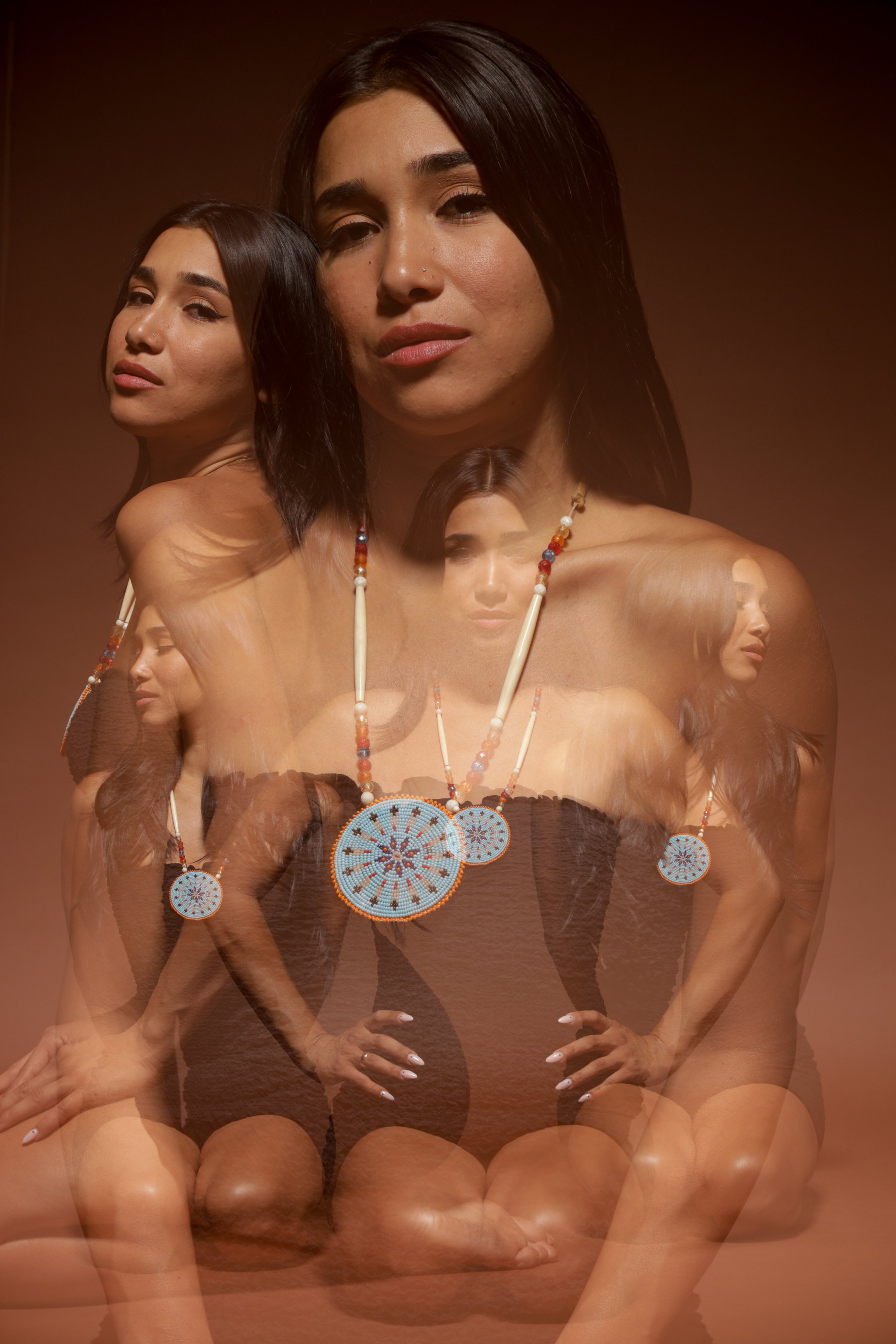 Multiple overlapping images of a woman with long dark hair, wearing a black top and beaded jewelry, against a brown background.