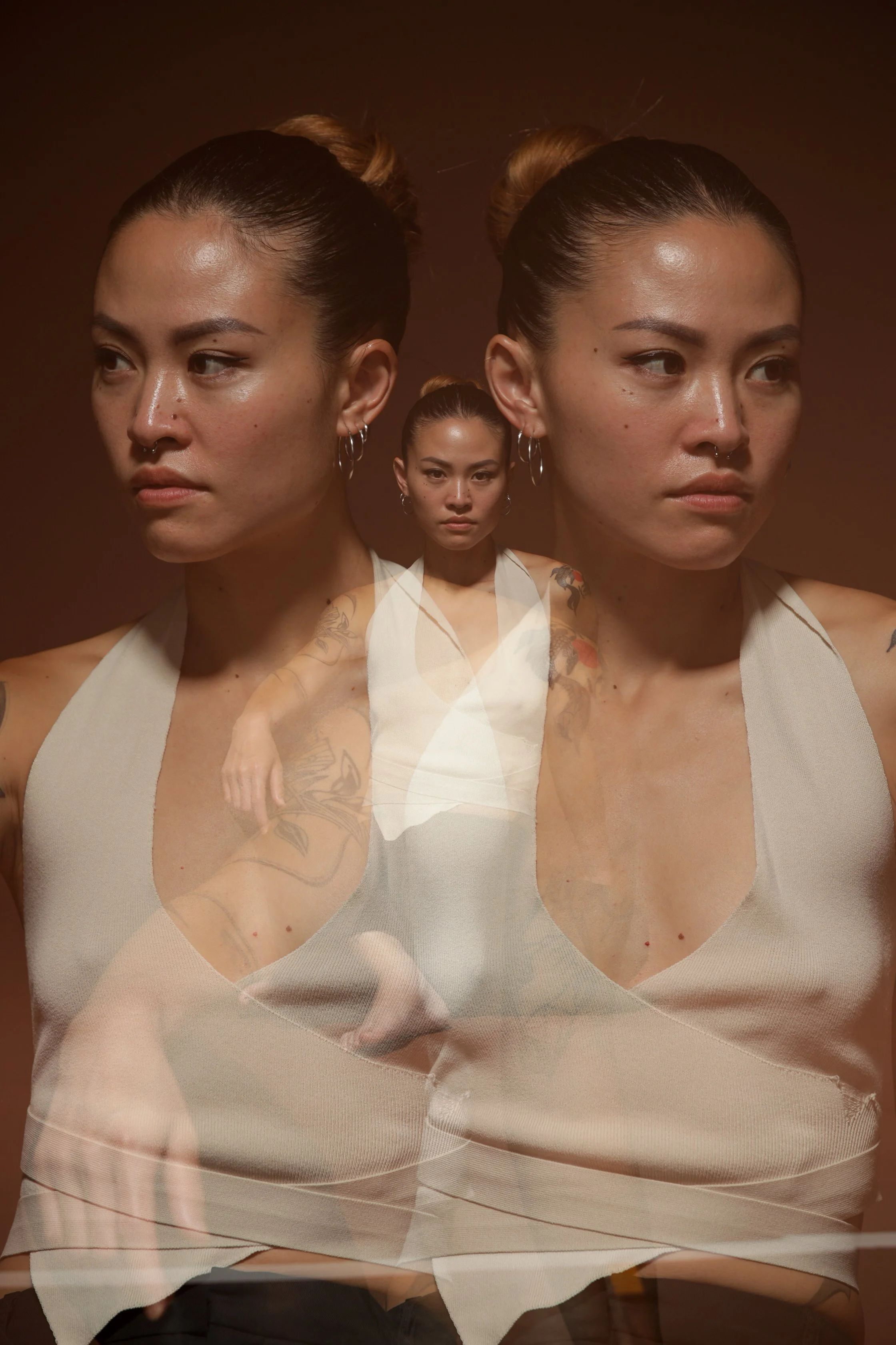 Multiple superimposed images of a woman with dark hair in a bun, wearing a light-colored tank top and hoop earrings, on a brown background.