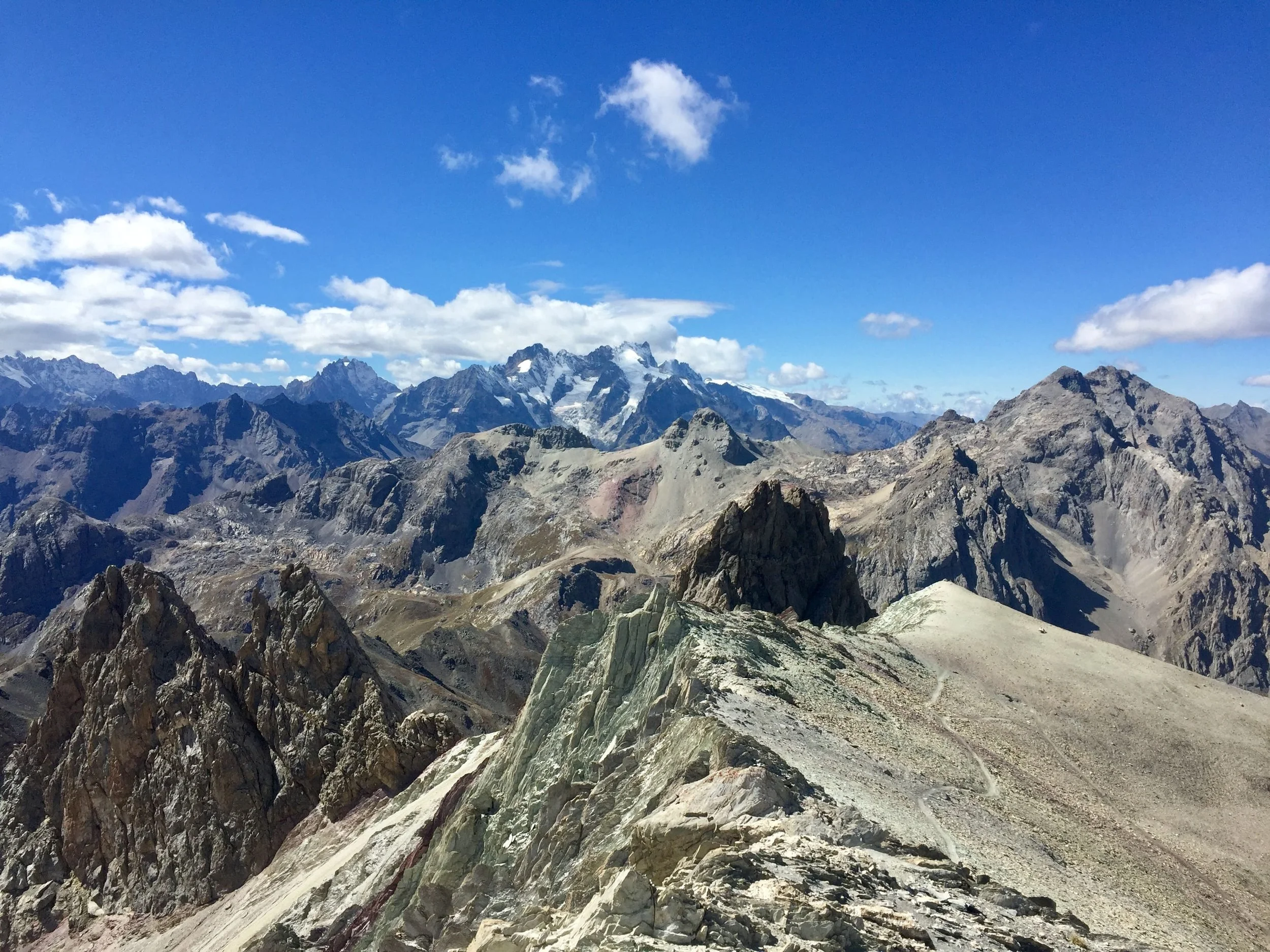Paysage de montagnes rocheuses sous un ciel bleu avec quelques nuages.