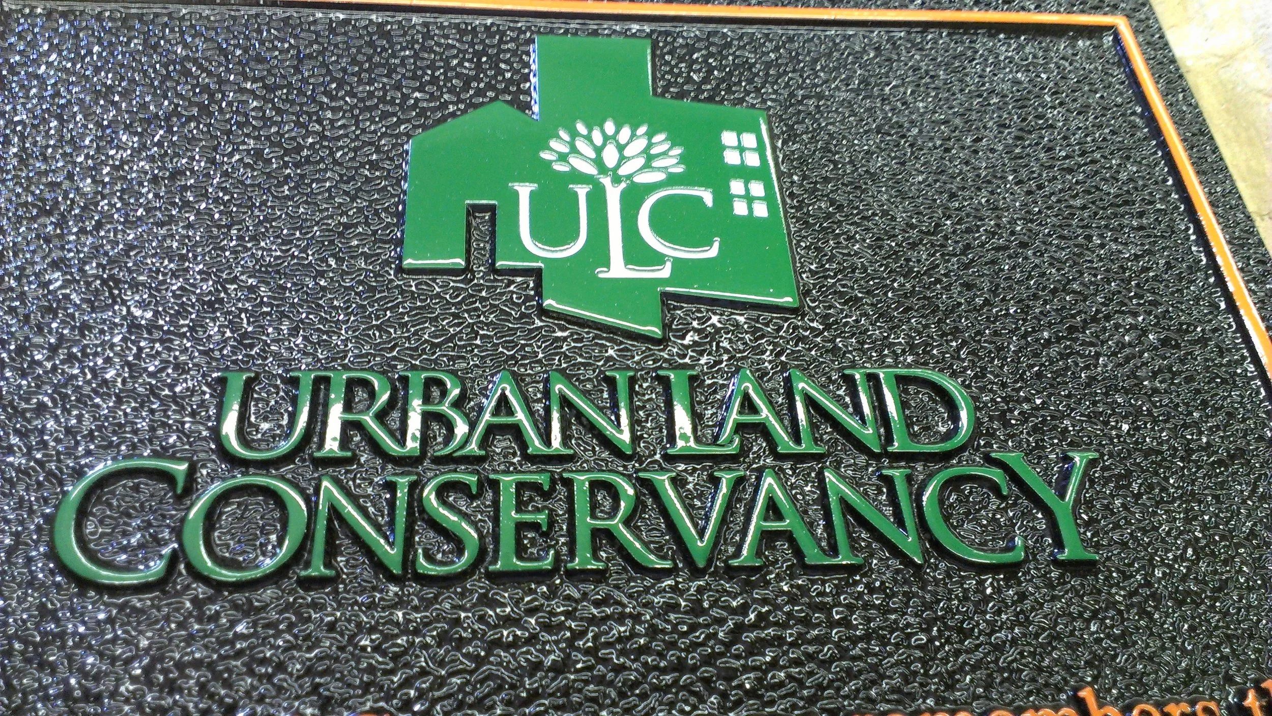 Urban Land Conservancy emblem displayed as a dimensional 3d bas relief plaque with raised lettering and textured surface common in architectural bas relief plaques.