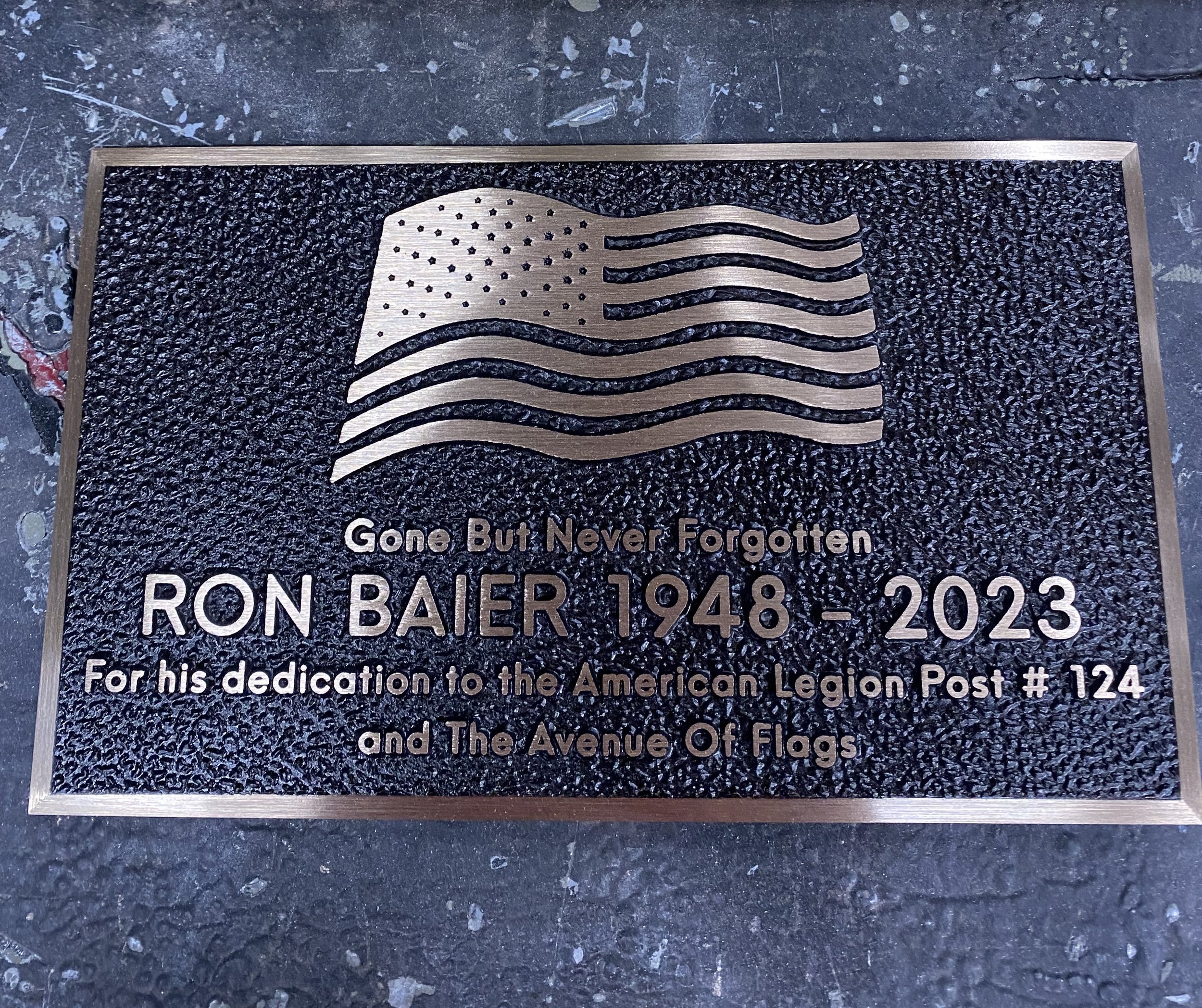Custom memorial plaques honoring Ron Baier featuring an American flag design, crafted as a bronze metal memorial plaque recognizing dedication to the American Legion and community service.