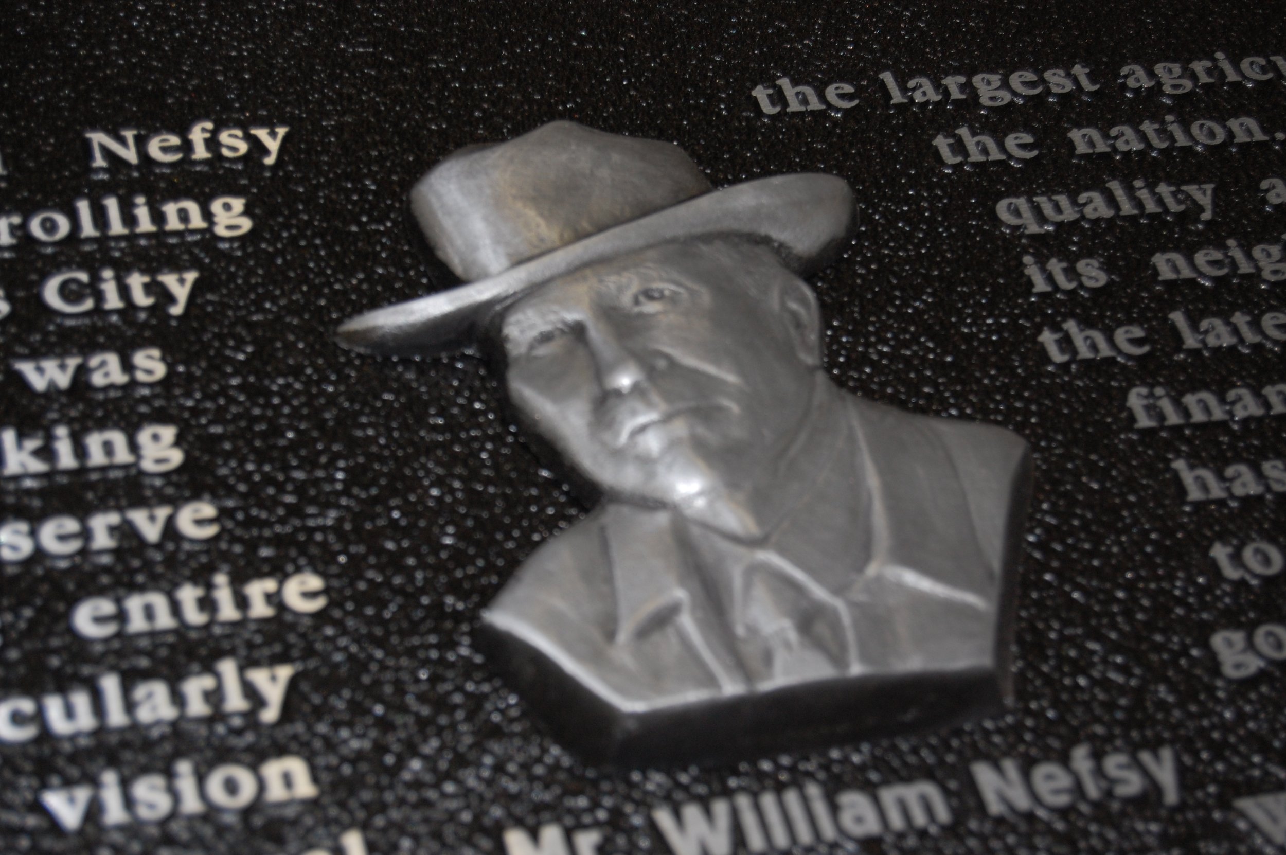 Sculpted portrait of a man in a hat cast as a detailed 3d bas relief plaque demonstrating dimensional artwork used in memorial bas relief plaques.