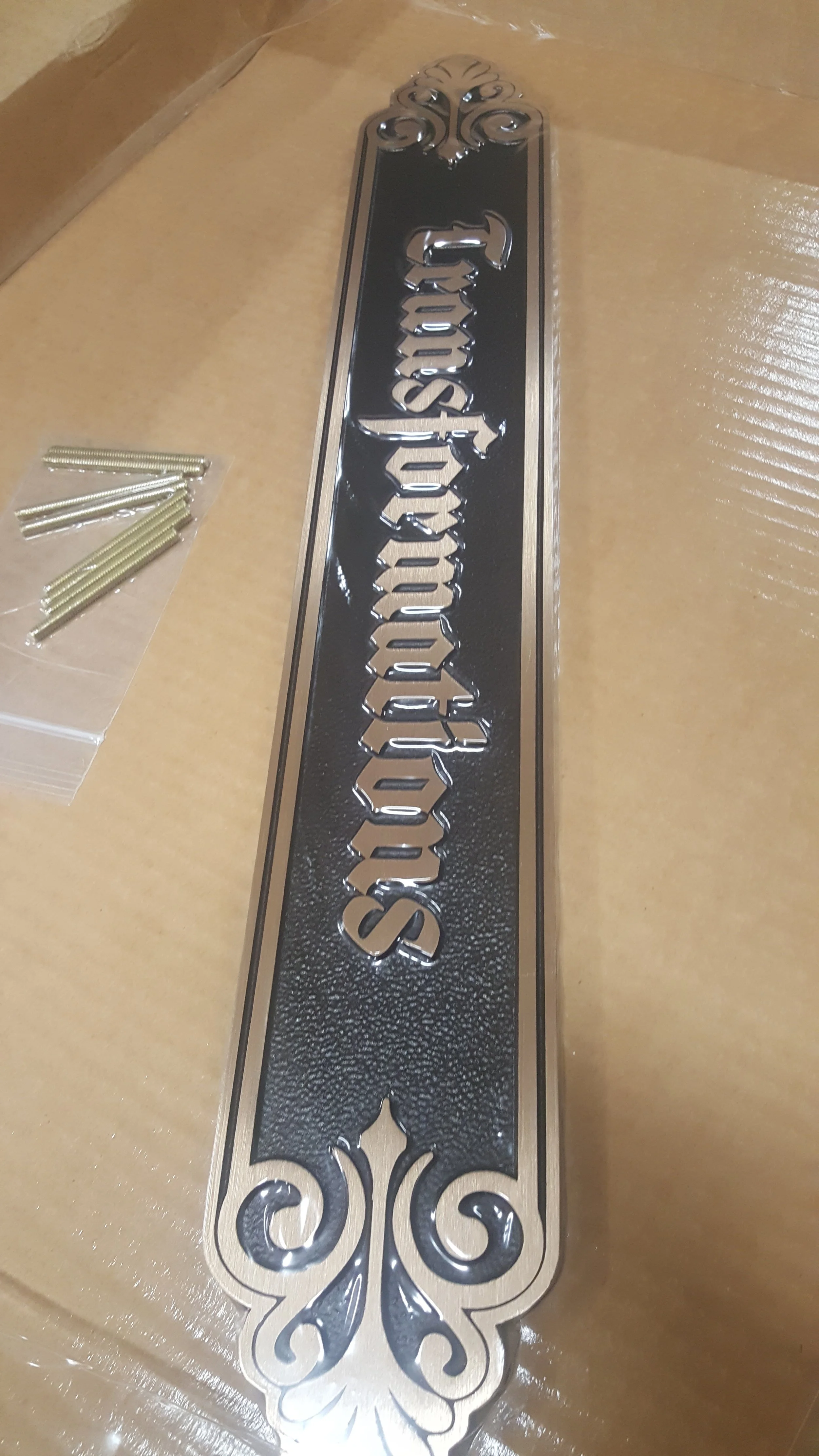 Decorative metal nameplate created as a 3d bas relief plaque with raised lettering and ornamental borders demonstrating custom bas relief plaques.