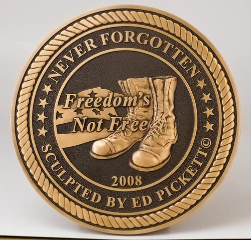 Round bronze memorial plaques with military boots design reading “Freedom’s Not Free,” crafted as custom memorial plaques and metal memorial tributes honoring veterans.