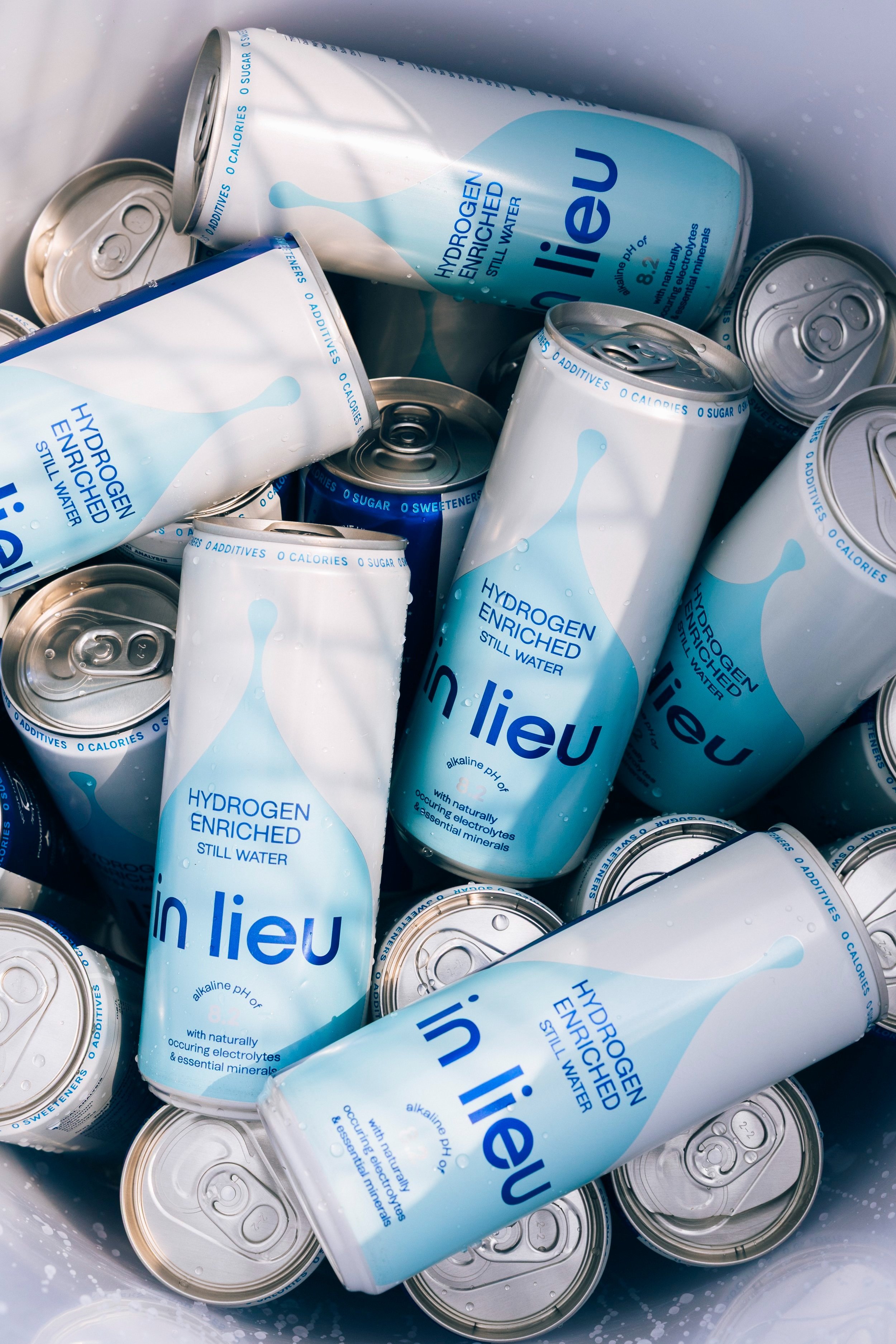 Several cans and bottles of in lieu hydrogen-enriched still water with blue and white packaging.