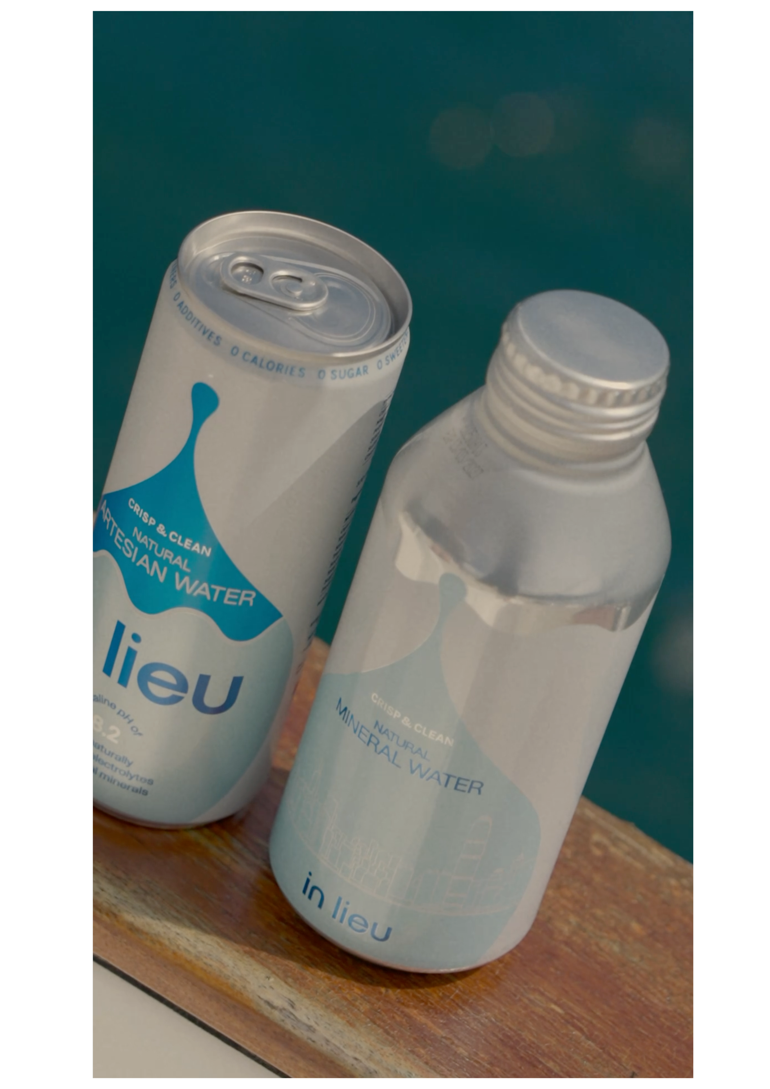 Cans and bottles of in lieu premium artesian water, featuring a pull-tab design, displayed on a wooden surface against a teal background. Showcasing the brand’s purity, natural filtration, heritage, and luxury hydration experience.