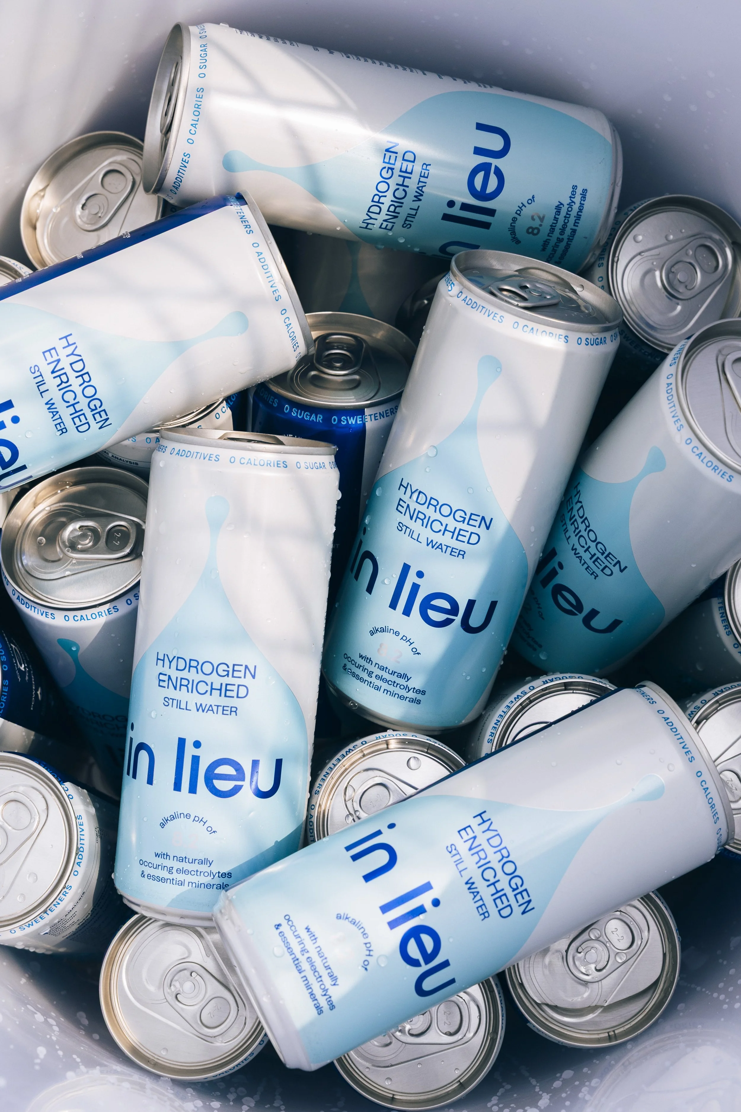 Multiple cans of in lieu hydrogen-enriched still water with blue and white labels.