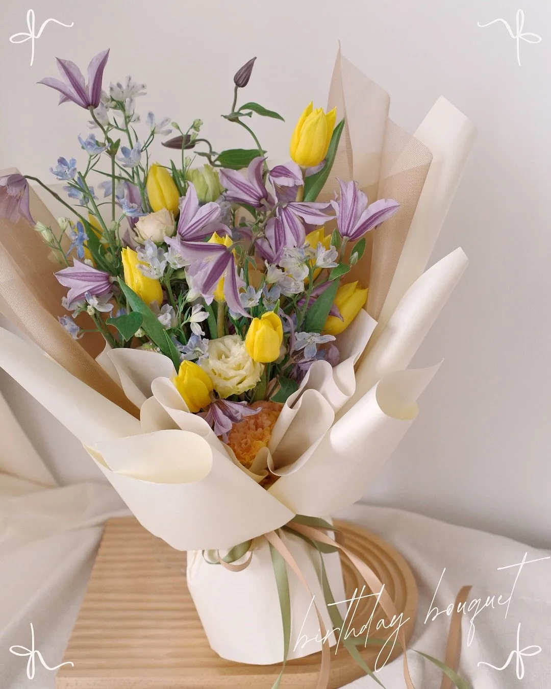 A pocket of spring &mdash; yellow tulips, lilac clematis, and blue mini delphiniums in a pastel daydream. Because birthdays deserve blooms that feel like sunshine 💛
