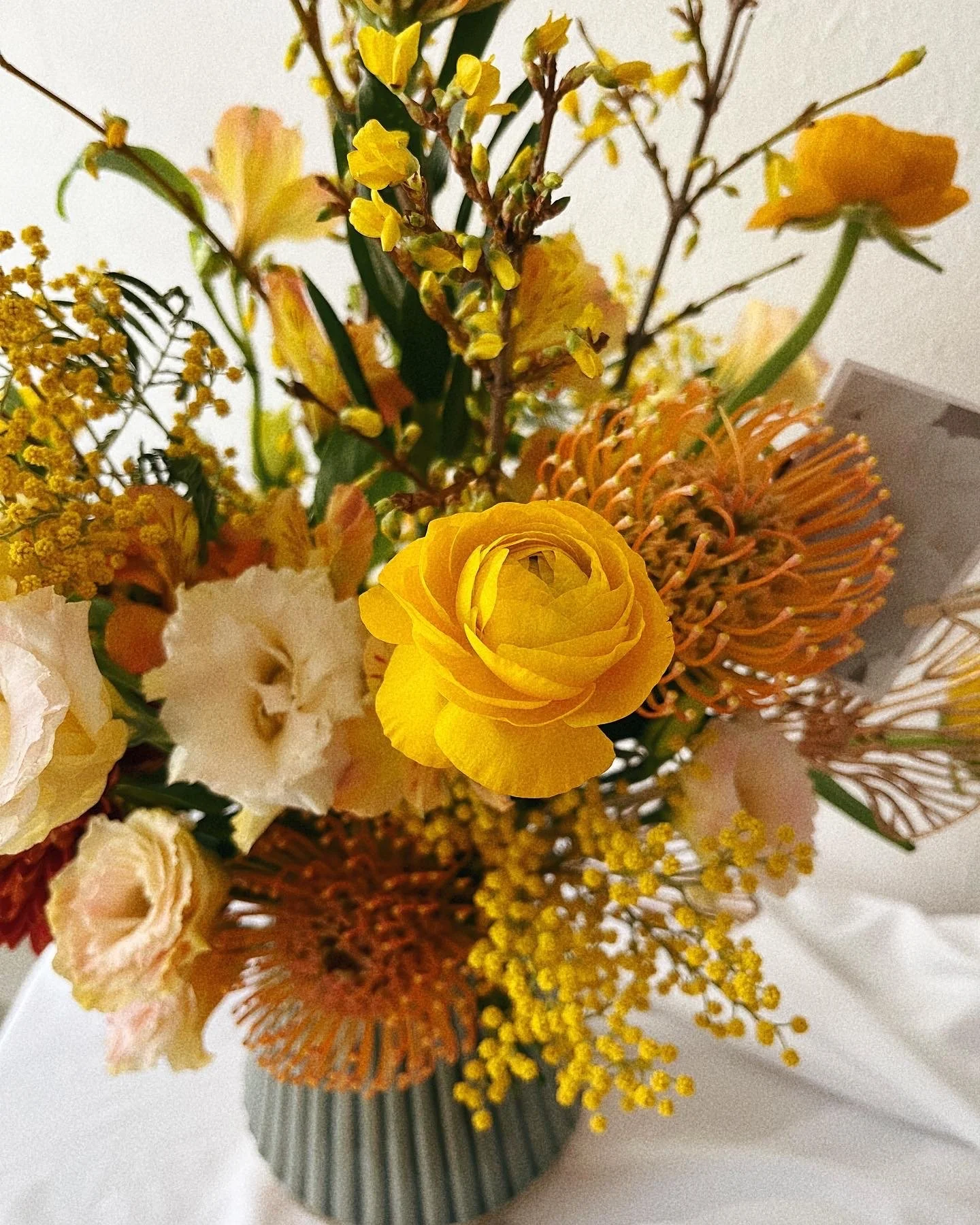 A colorful bouquet of yellow, white, and orange flowers in a striped vase.