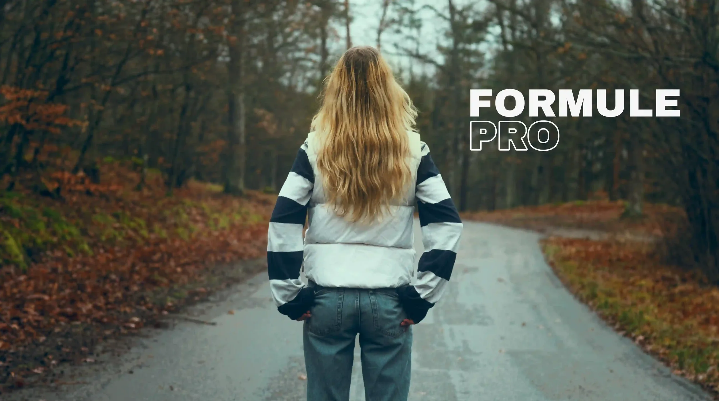 Une personne vue de dos, marchant sur une route forestière en automne, portant une veste à rayures et des jeans, avec le texte "FORMULE PRO" sur l'image.