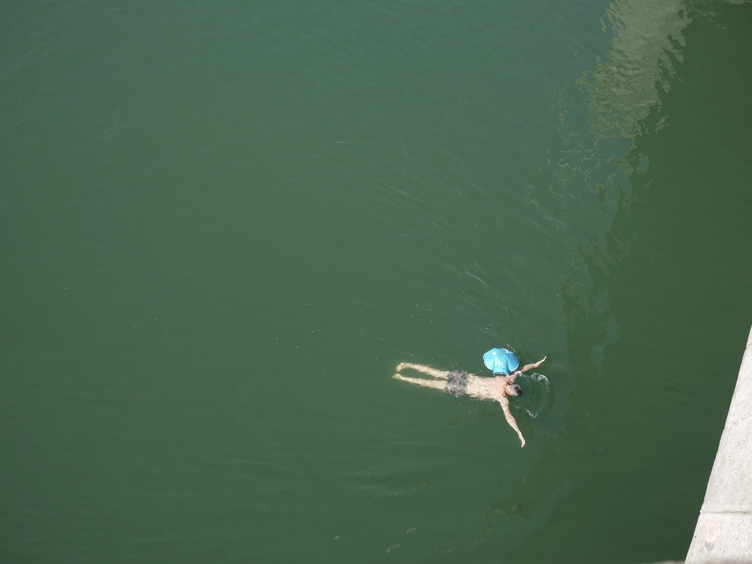 Escaping the heat – a person floating downstream on the Rhine with their dry bag