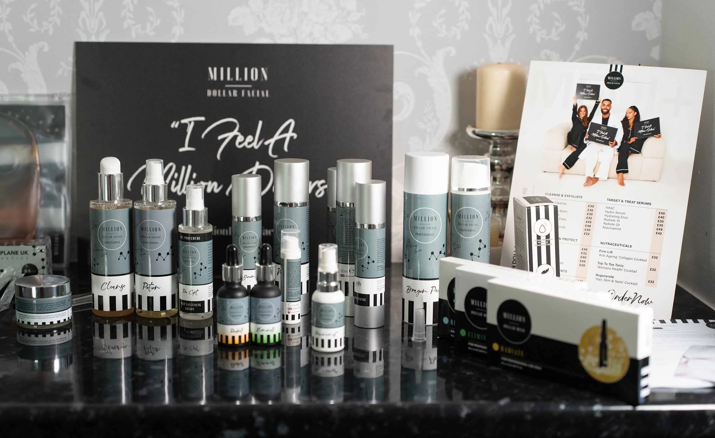 Collection of Million Dollar Facial skincare products, including bottles and jars, arranged on a black countertop with promotional signs in the background.