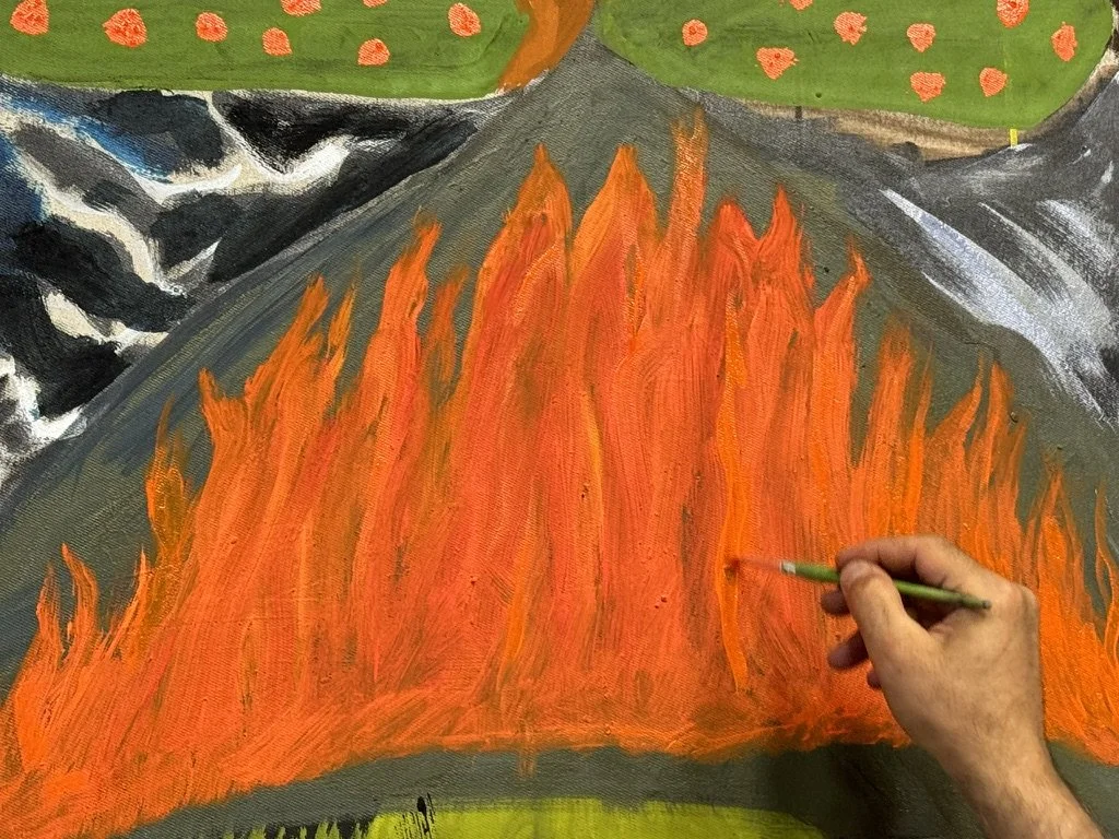 Ein Künstler malt mit einem Pinsel orange Flammen auf eine große Leinwand, im Hintergrund sind grüne Hügel mit roten Blumen. Der Malprozess ist sichtbar, während die Hand des Künstlers die Flammen gestaltet.