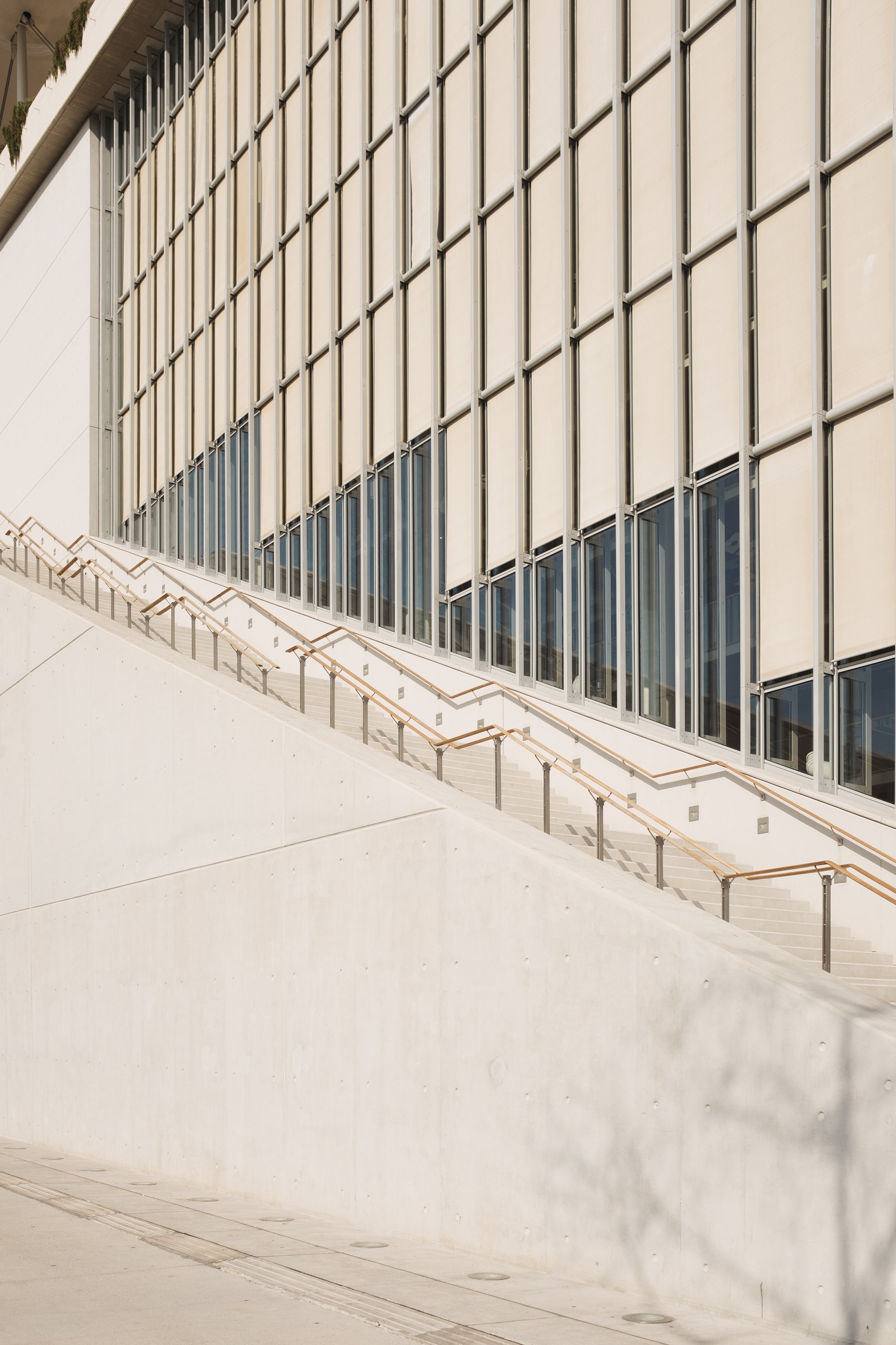 Modern building facade with large glass windows and a sloped staircase with handrails.