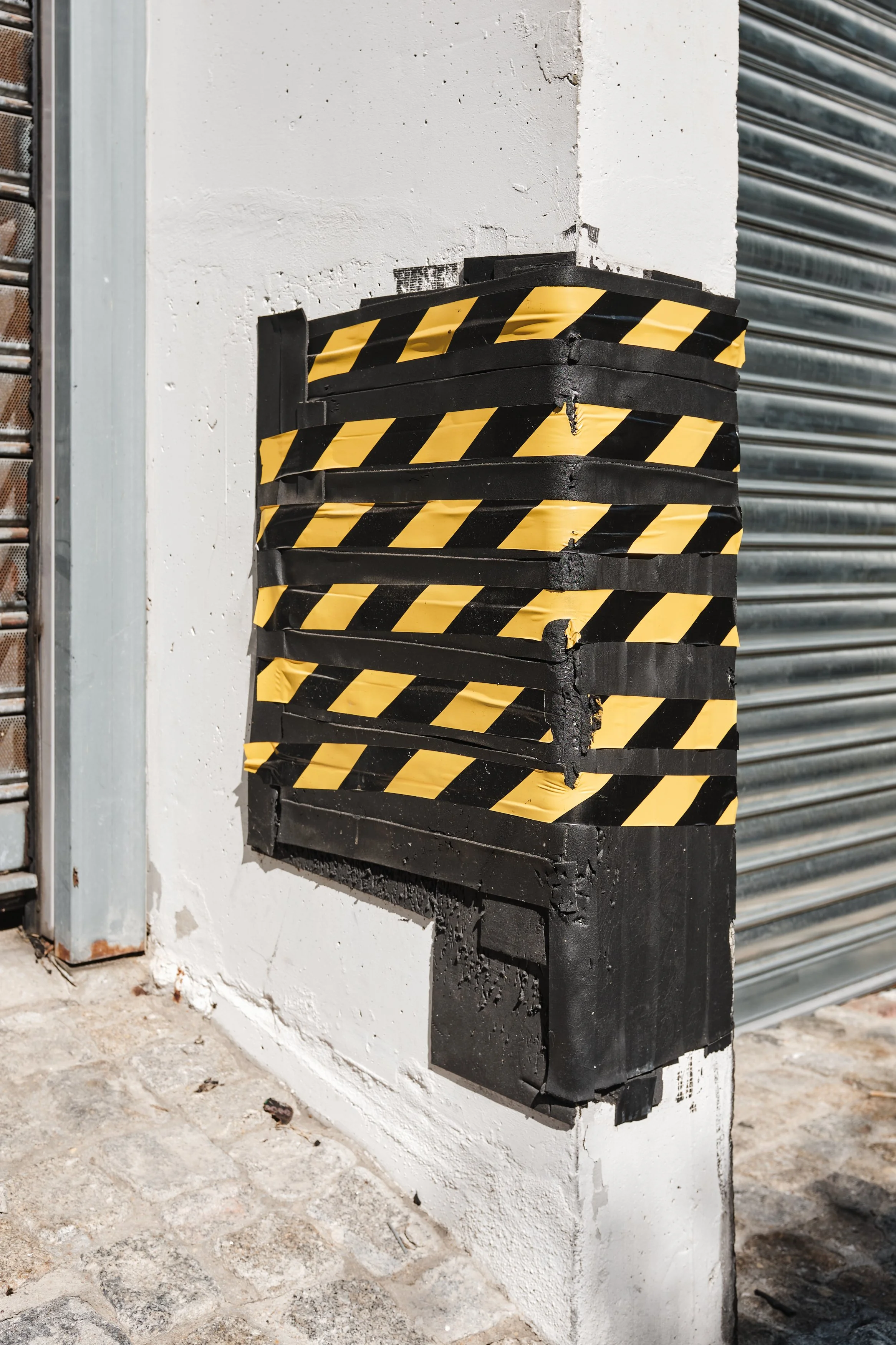 A black and yellow barricade or caution barrier mounted on a white wall.
