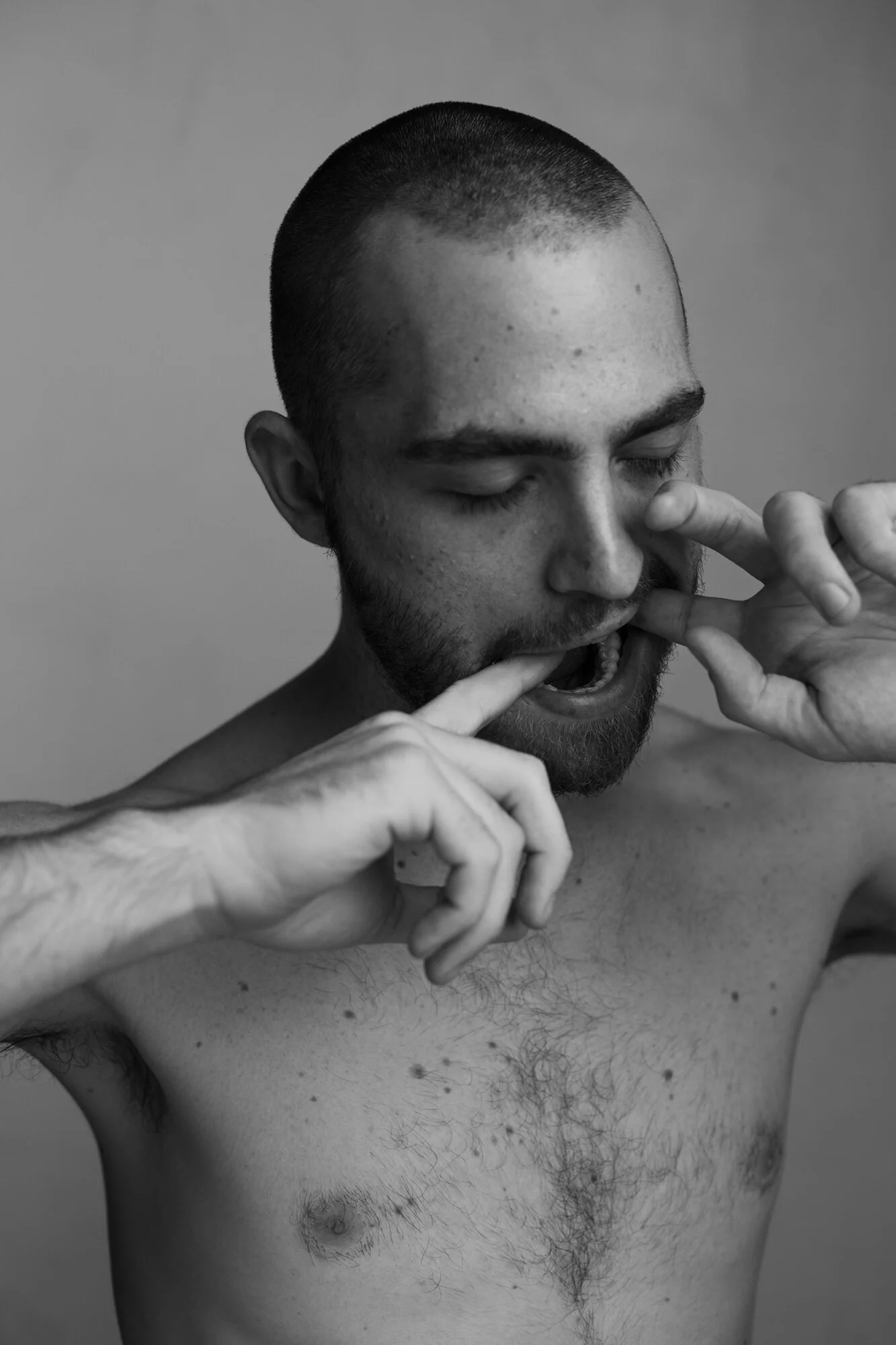 Schwarzweiß Studiofoto von jungem Mann, situativ mit Fingern im Mund und geschlossenen Augen