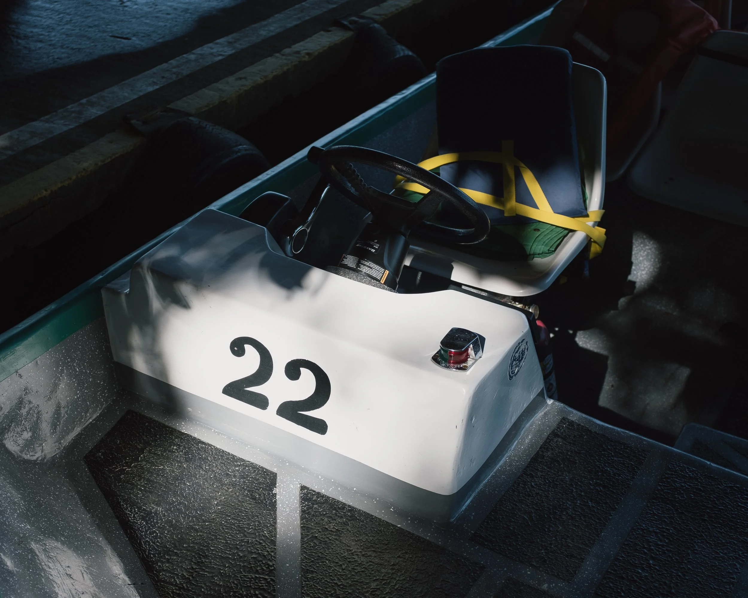 A small white electric golf cart with the number 22 on its front, parked on a wet surface in a dimly lit area.