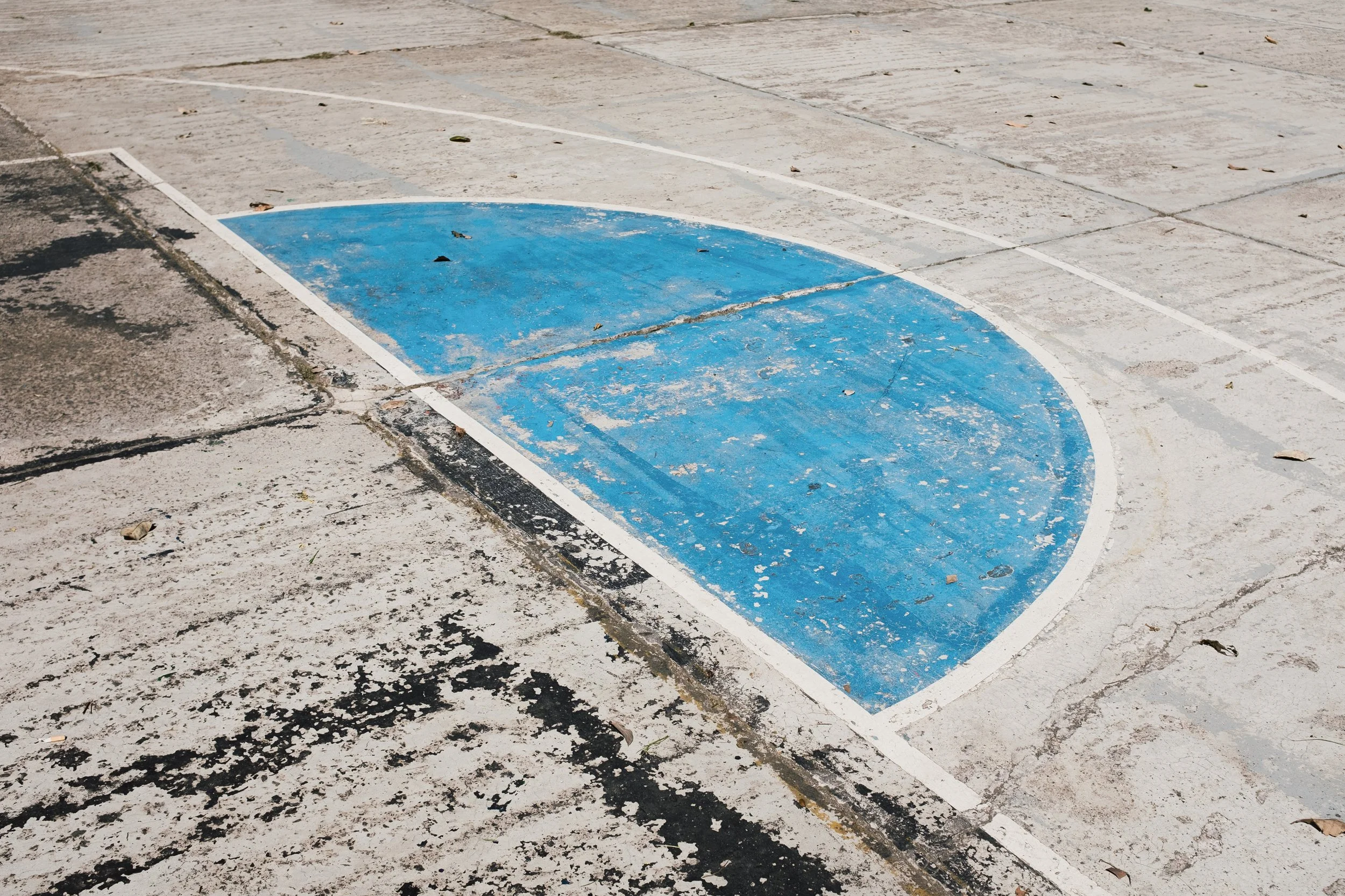 A close-up of a blue semi-circular parking space on a concrete surface, which appears to be a designated parking zone for a disabled parking spot. The area shows signs of wear and dirt.