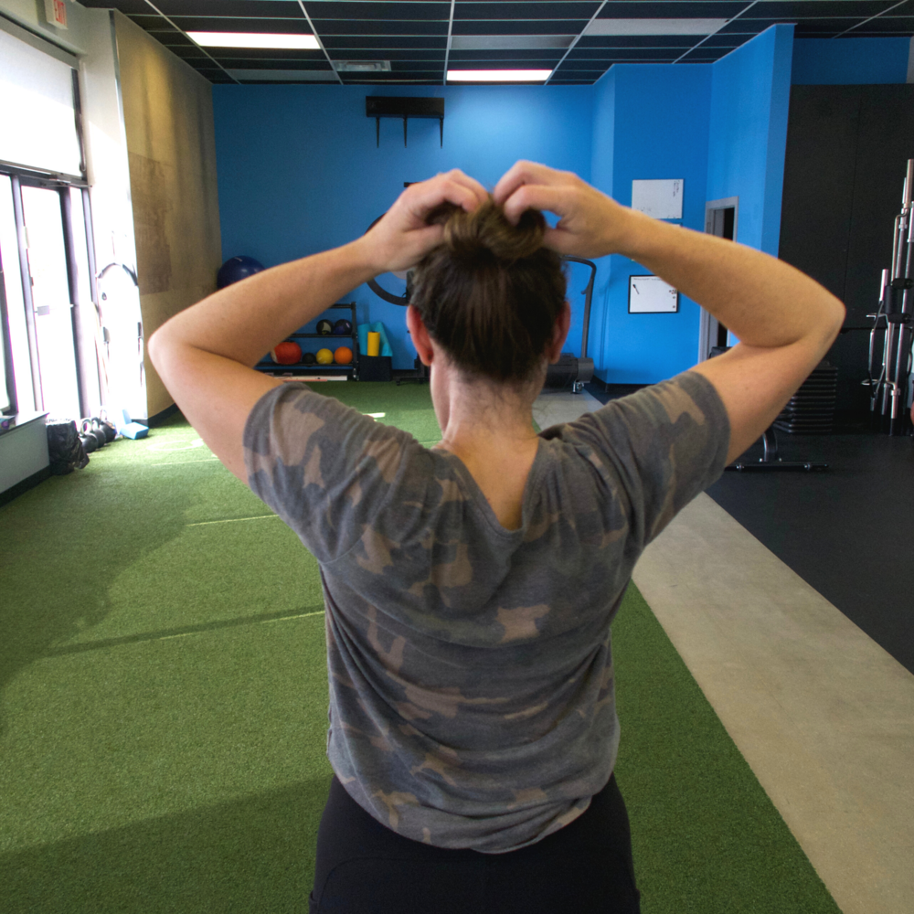 the back off female with hands overhead touching her head