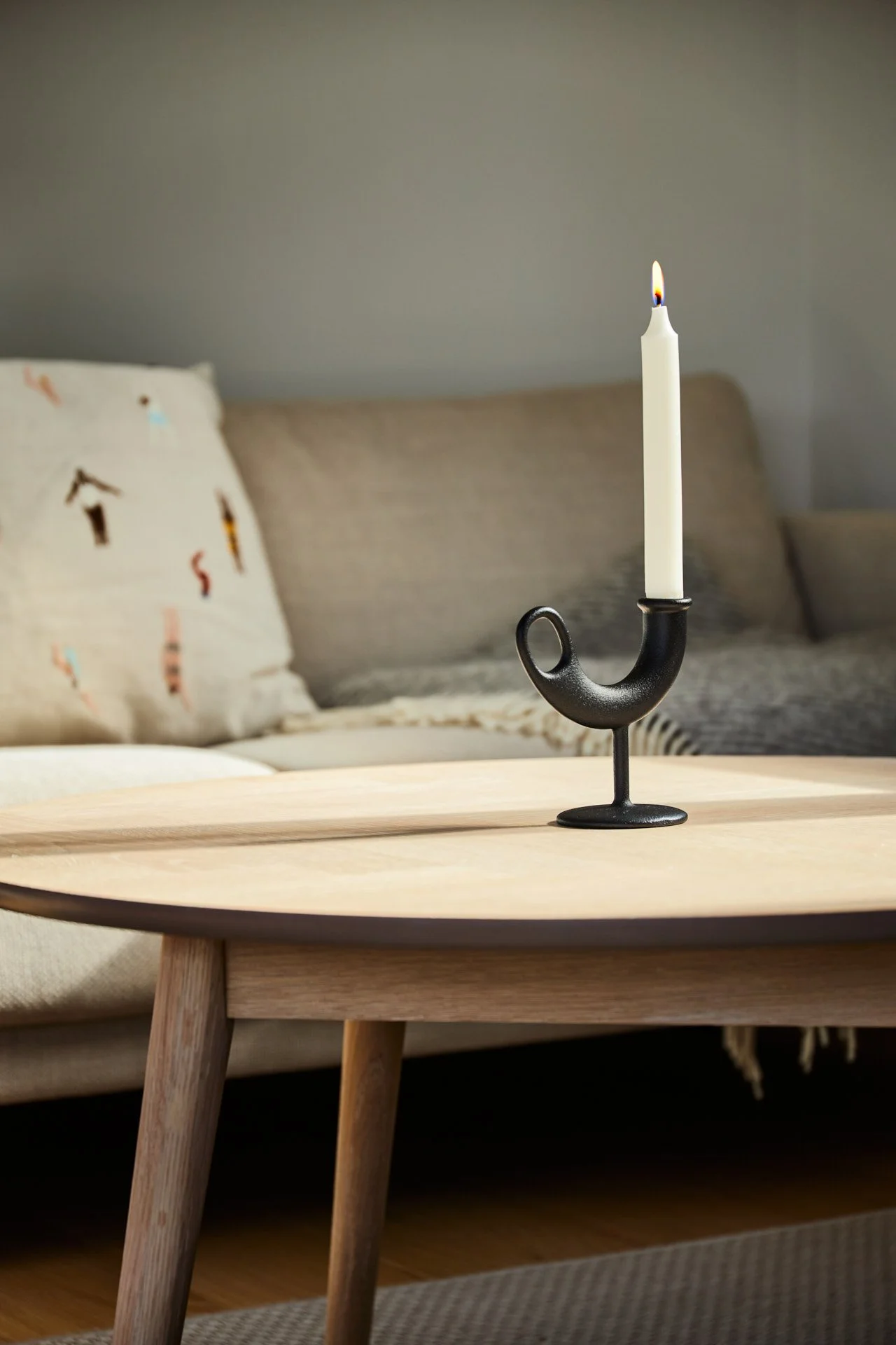 Ildhanen lysestake designet av Anderssen & Voll. Mykt sollys fra siden, varme farger, avslappet skandinavisk interiør.