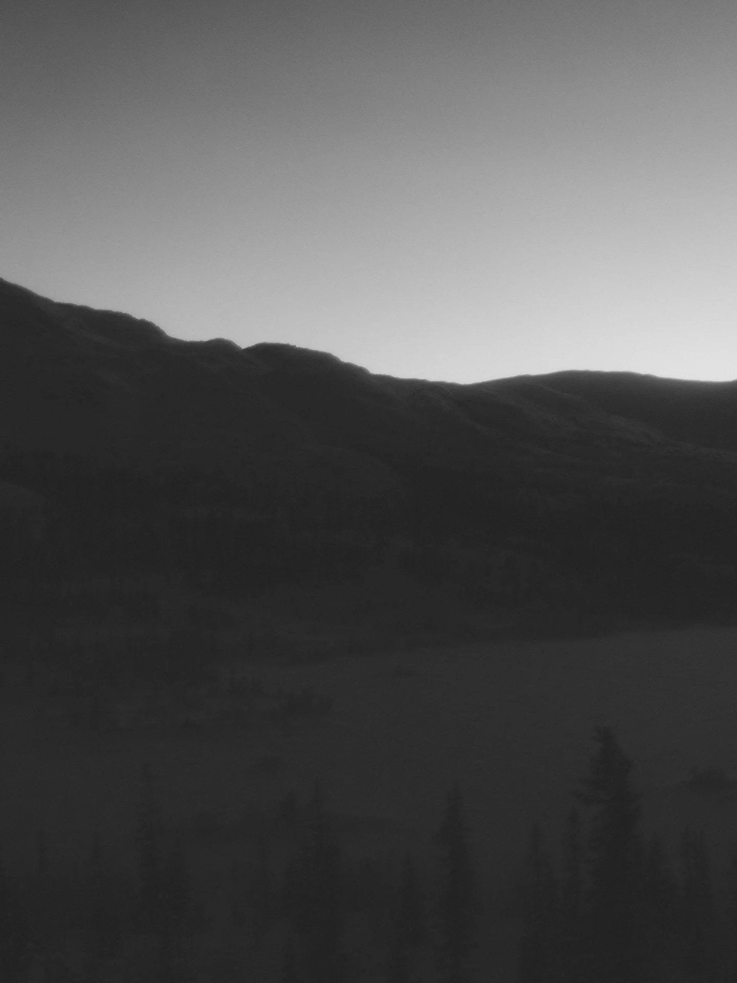 Dramatisk landskap med fjell og mildt lys, svart-hvitt.