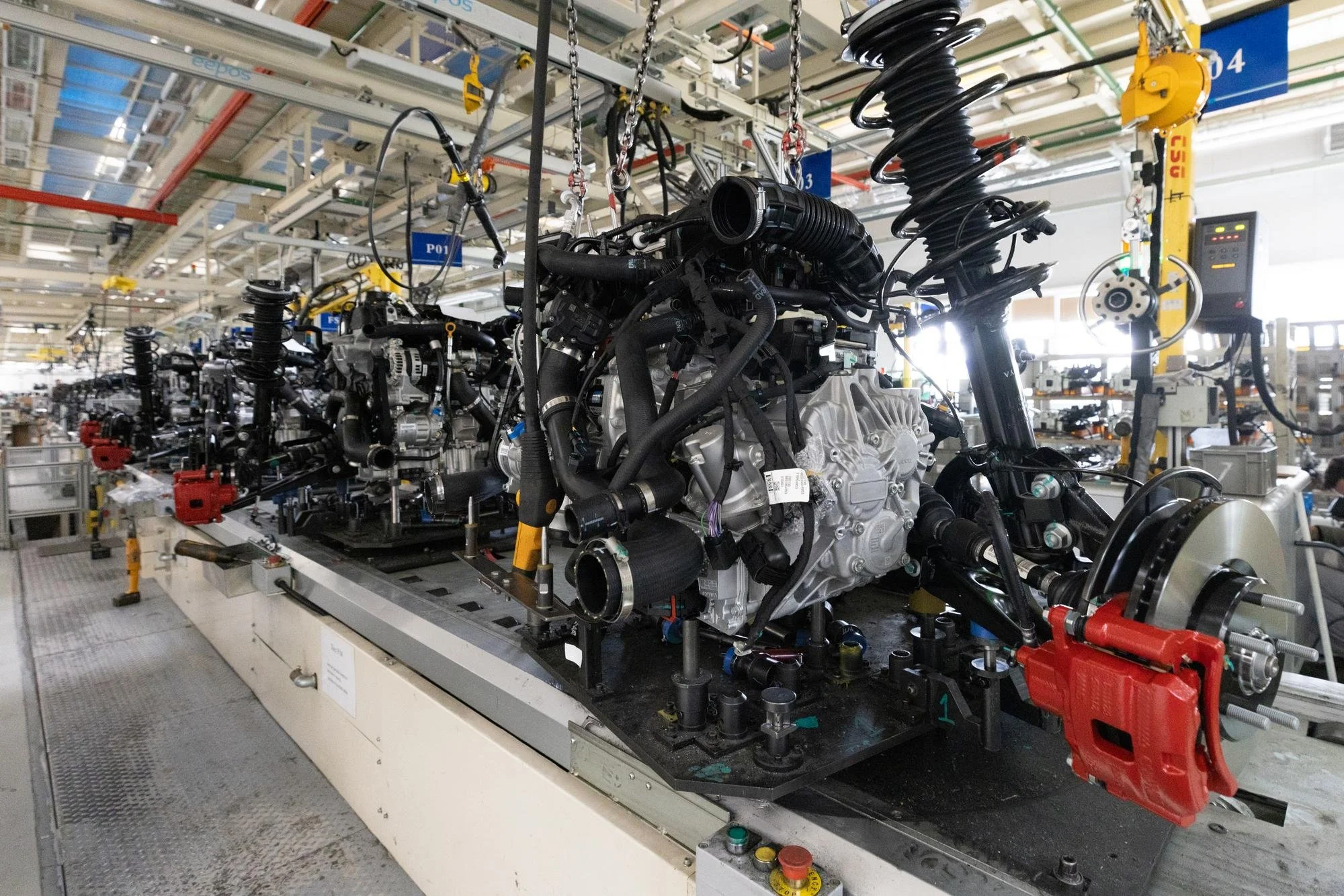 A large industrial robot assembly line working on car engines inside a factory.