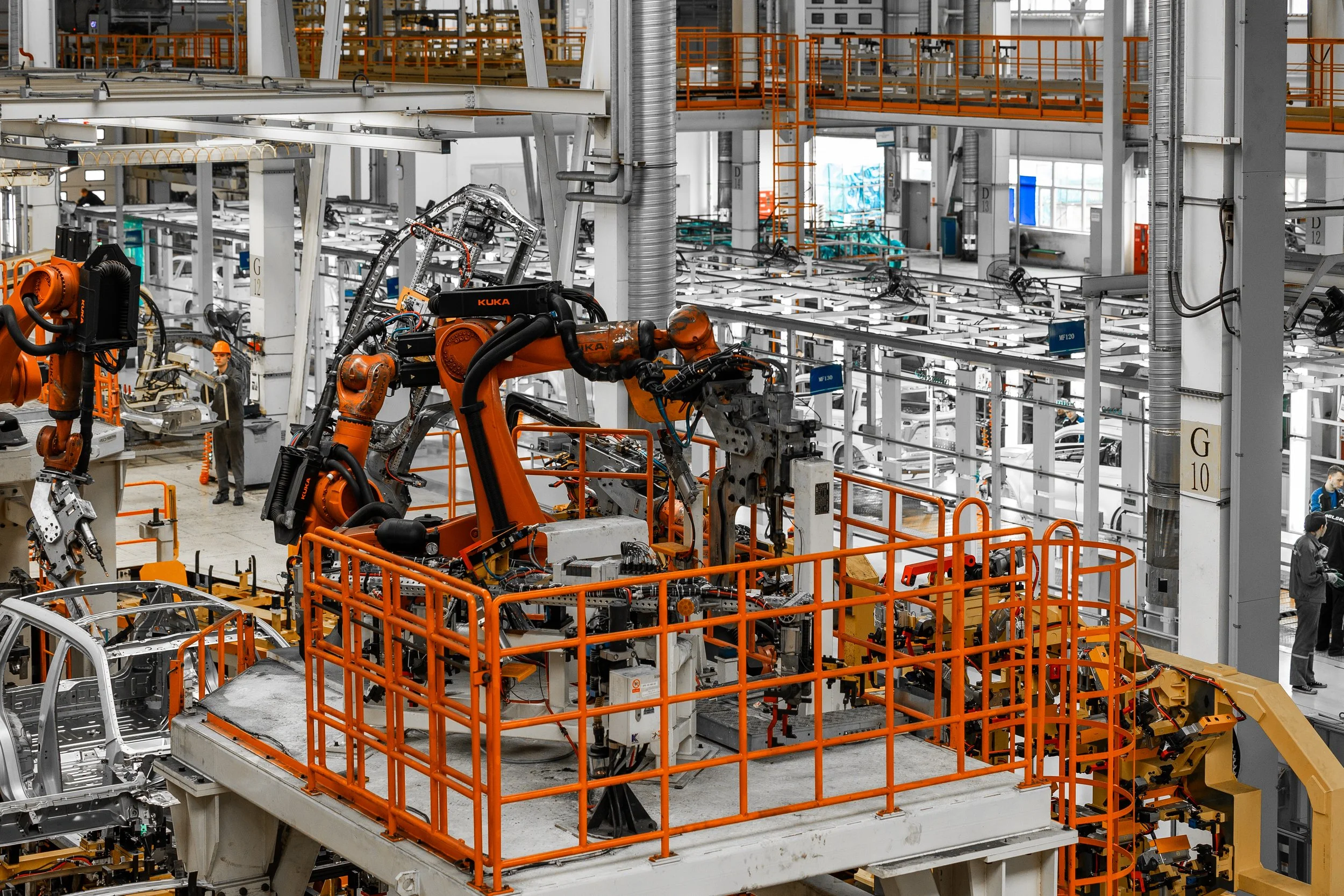 Factories with robotic arms assembling vehicles.