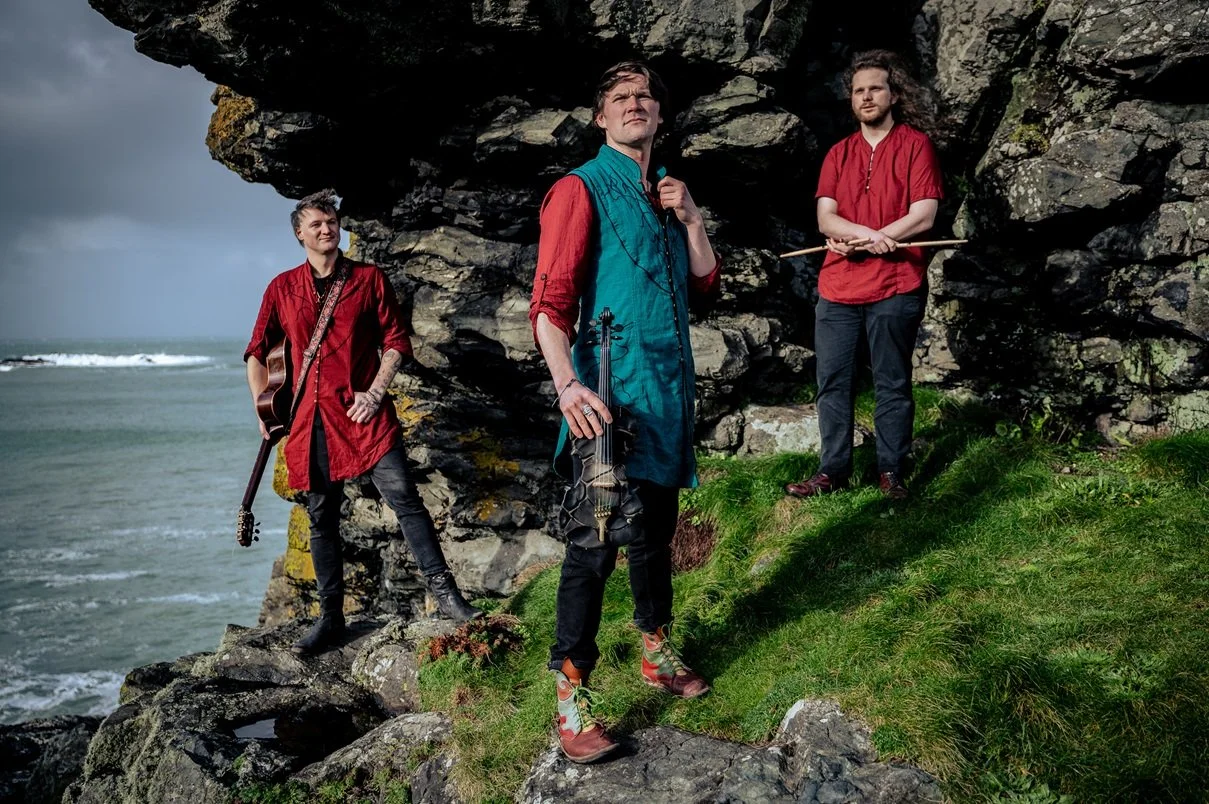 Three men with musical instruments by the sea
