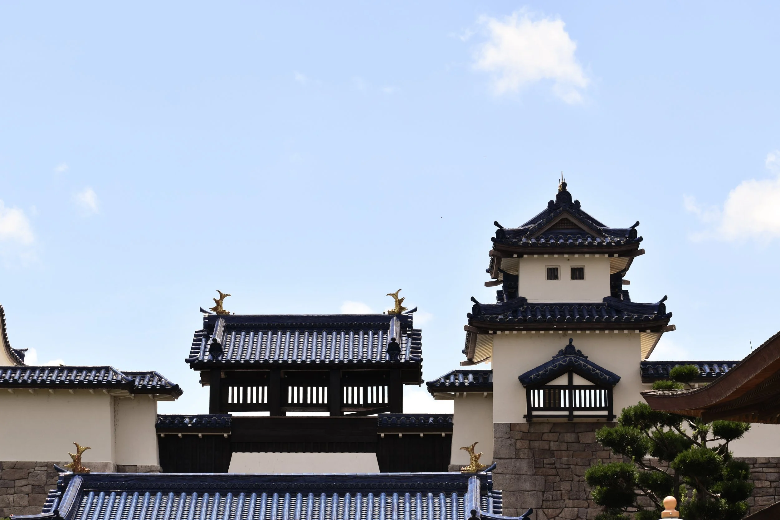 Traditional Asian temple with blue-tiled roofs, golden dragon ornaments, and a clear blue sky in the background.