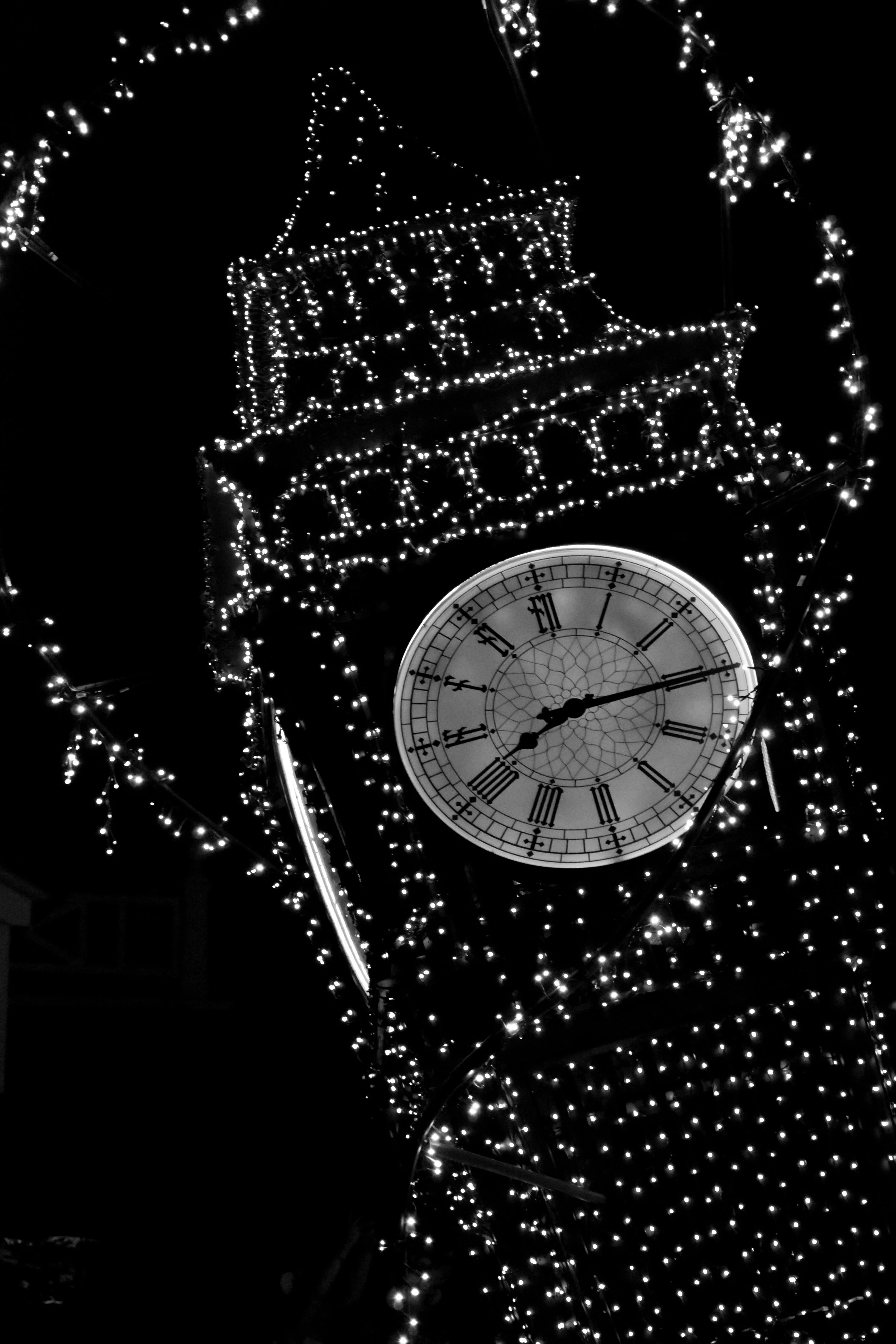 A clock showing 11:11 with festive holiday lights and decorations around it.