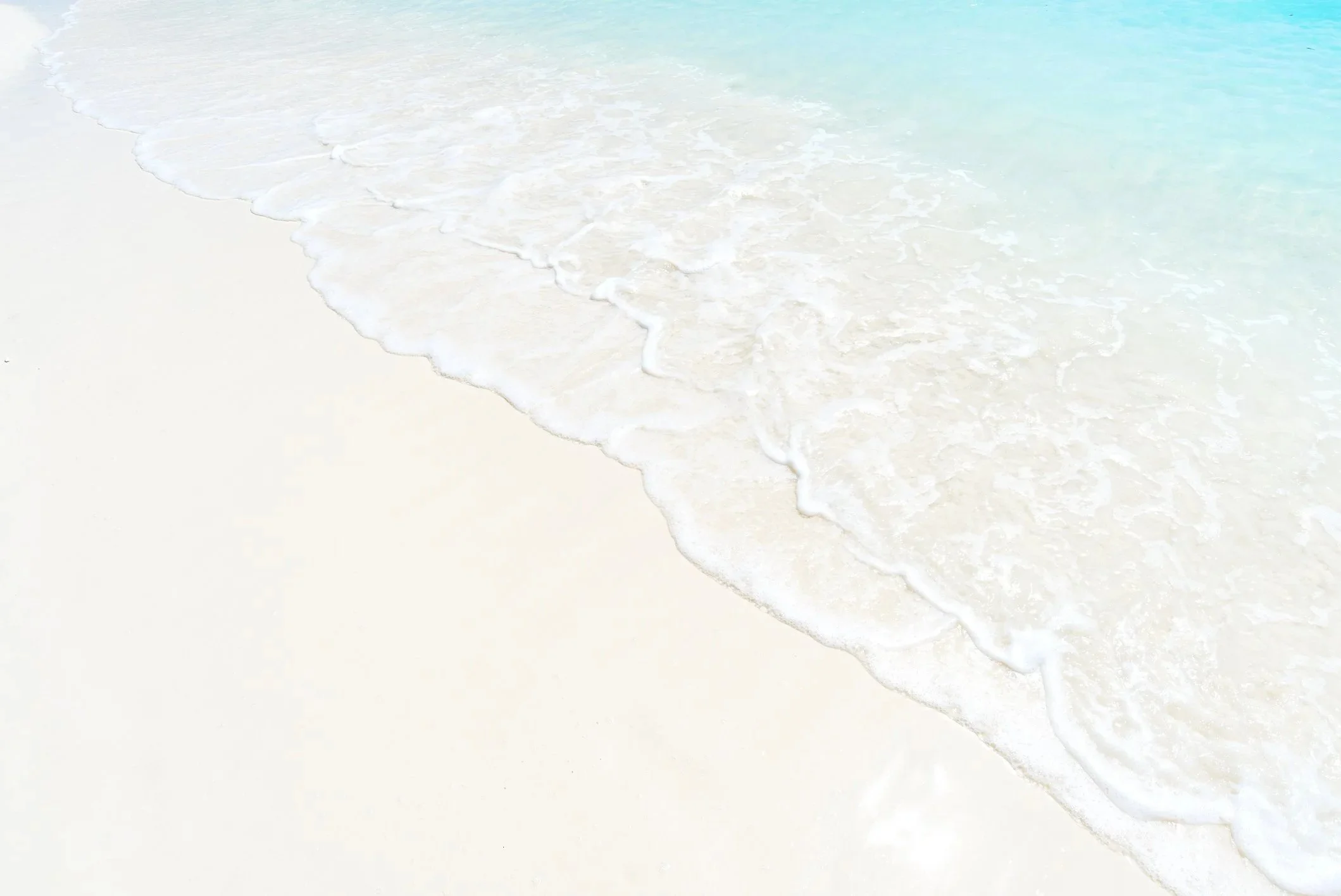 A sandy beach with gentle waves washing onto the shore, watercolor style.