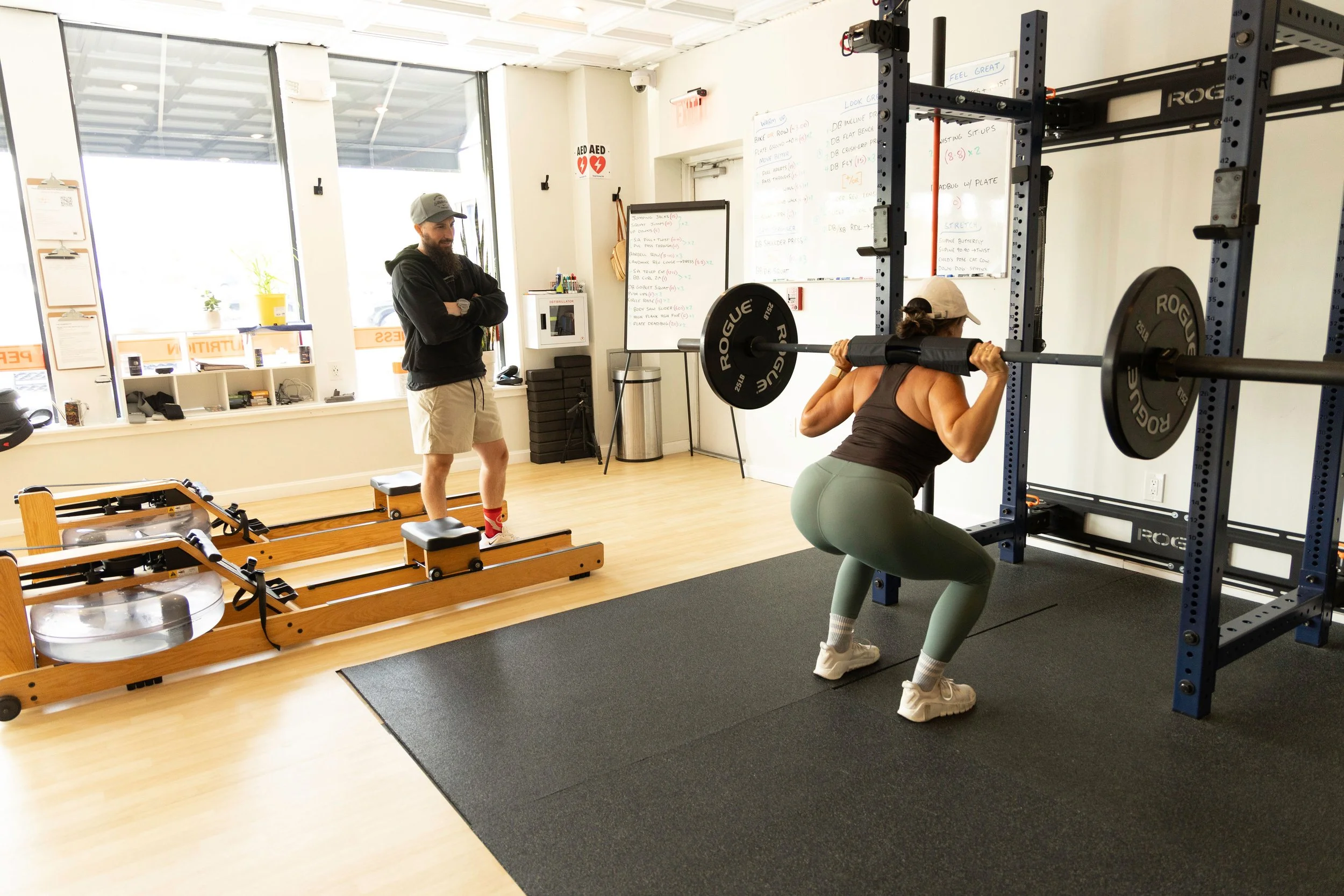 Pre-menopausal woman doing heavy back squat under coach garretts supervision.