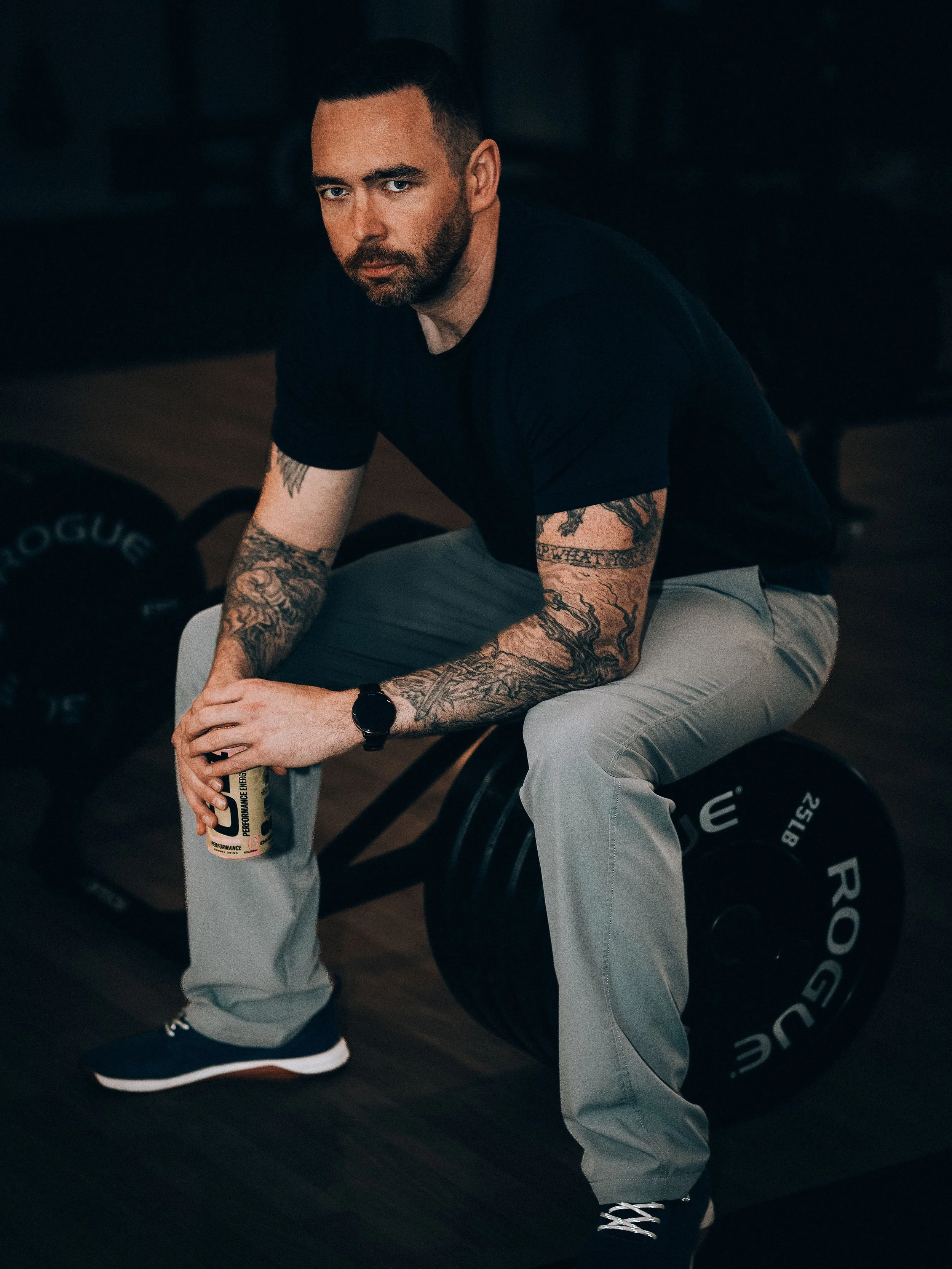 Owner Christopher Ryan sitting on weights drinking an energy drink while doing a workout at the genesis fit