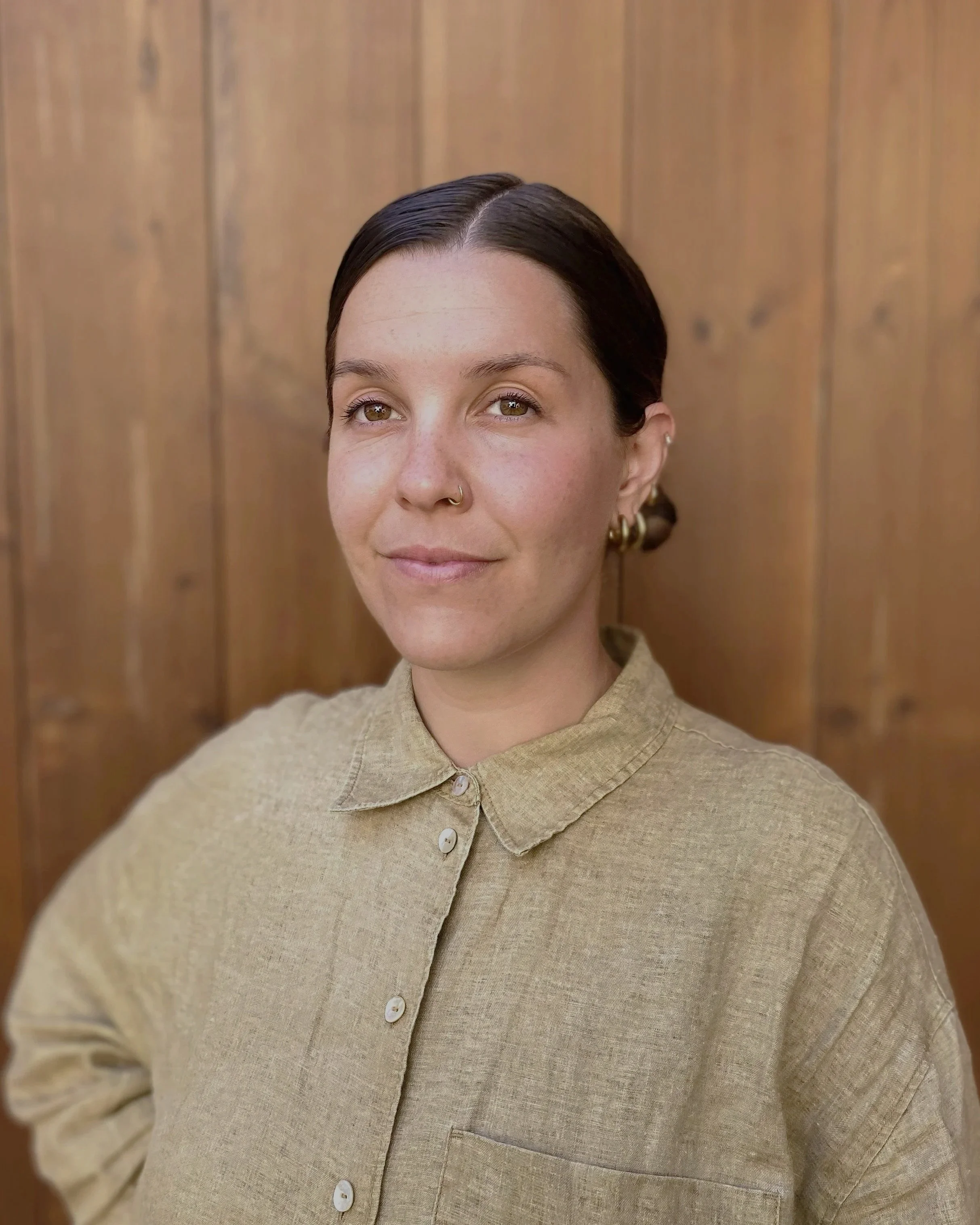Portrait of Bianca Inês Pedro,  standing in front of a wooden wall.