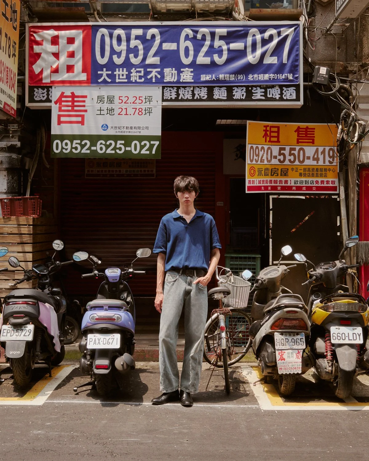 Male model posing between scooters on a Taipei street photographed by Pedro Márnez