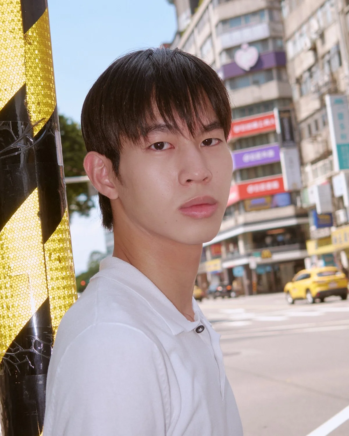 Male model in a white polo shirt photographed on a Taipei street by Pedro Márnez